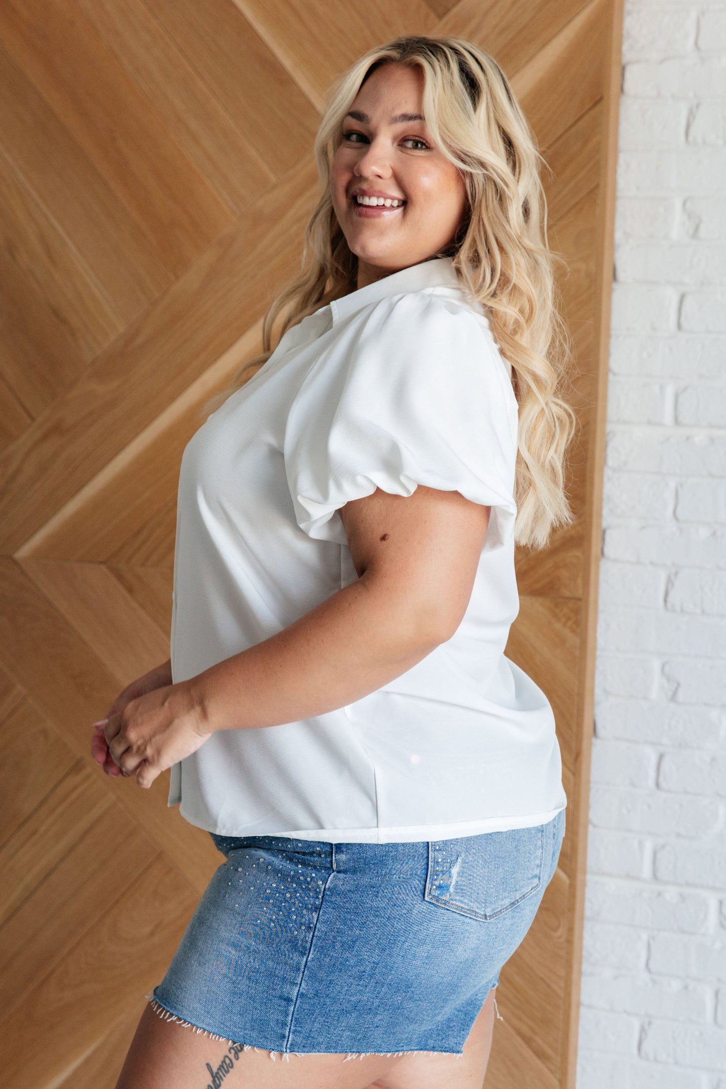 Women's white blouse with crinkle woven fabric, collared neckline, short balloon sleeves with elastic cuffs, and a front button closure.