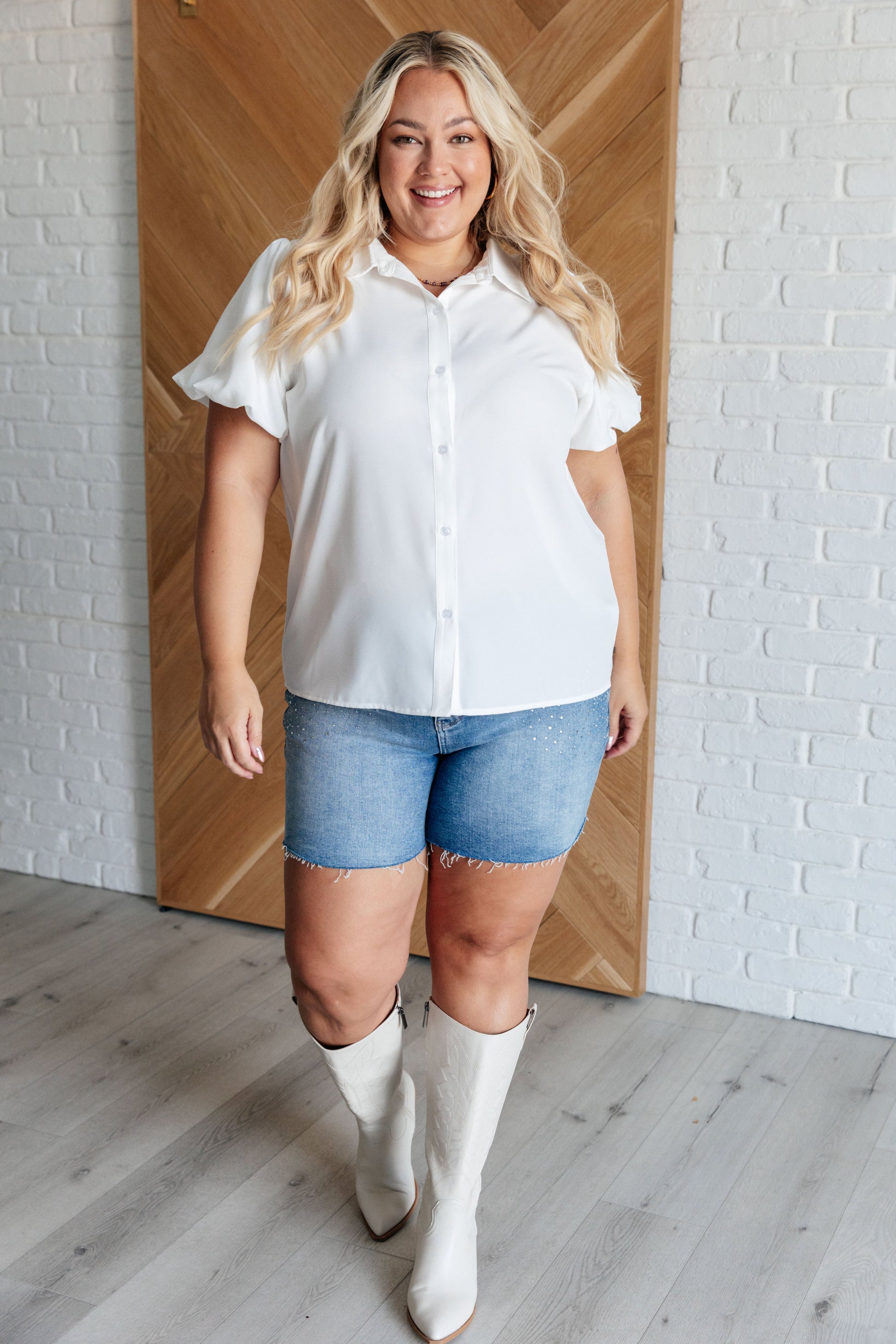 Women's white blouse with crinkle woven fabric, collared neckline, short balloon sleeves with elastic cuffs, and a front button closure.