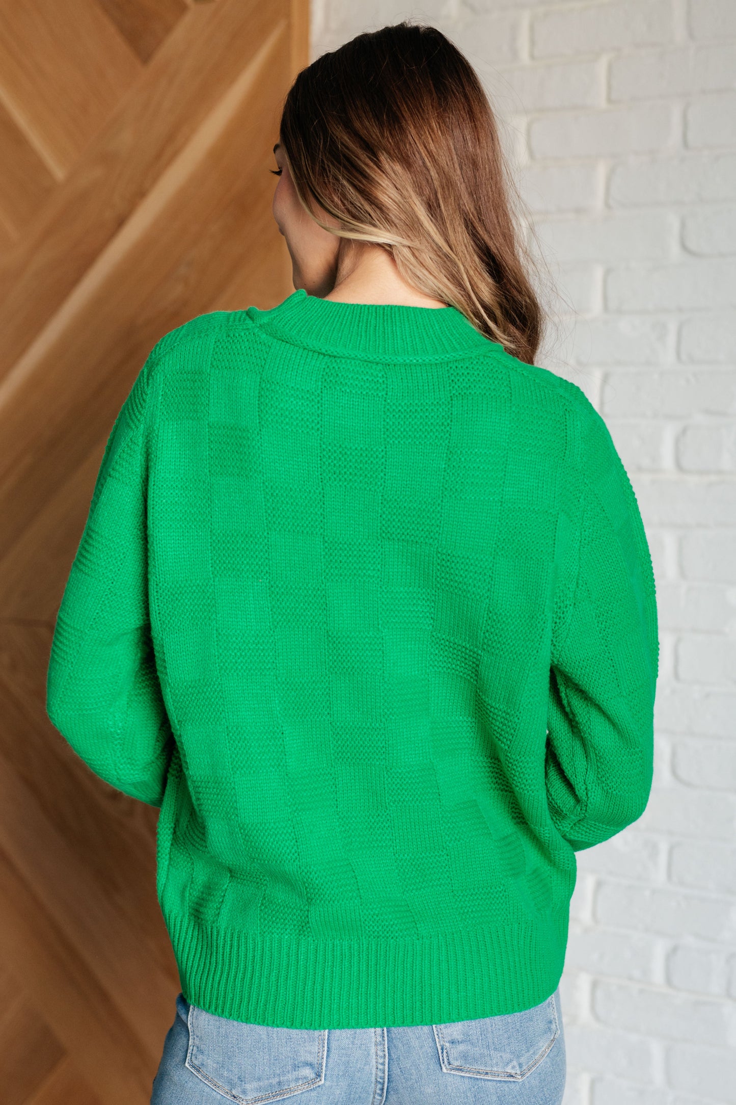 Green women's sweater with a monochromatic checker pattern, round ribbed neckline, long sleeves, and ribbed cuffs and hemline.