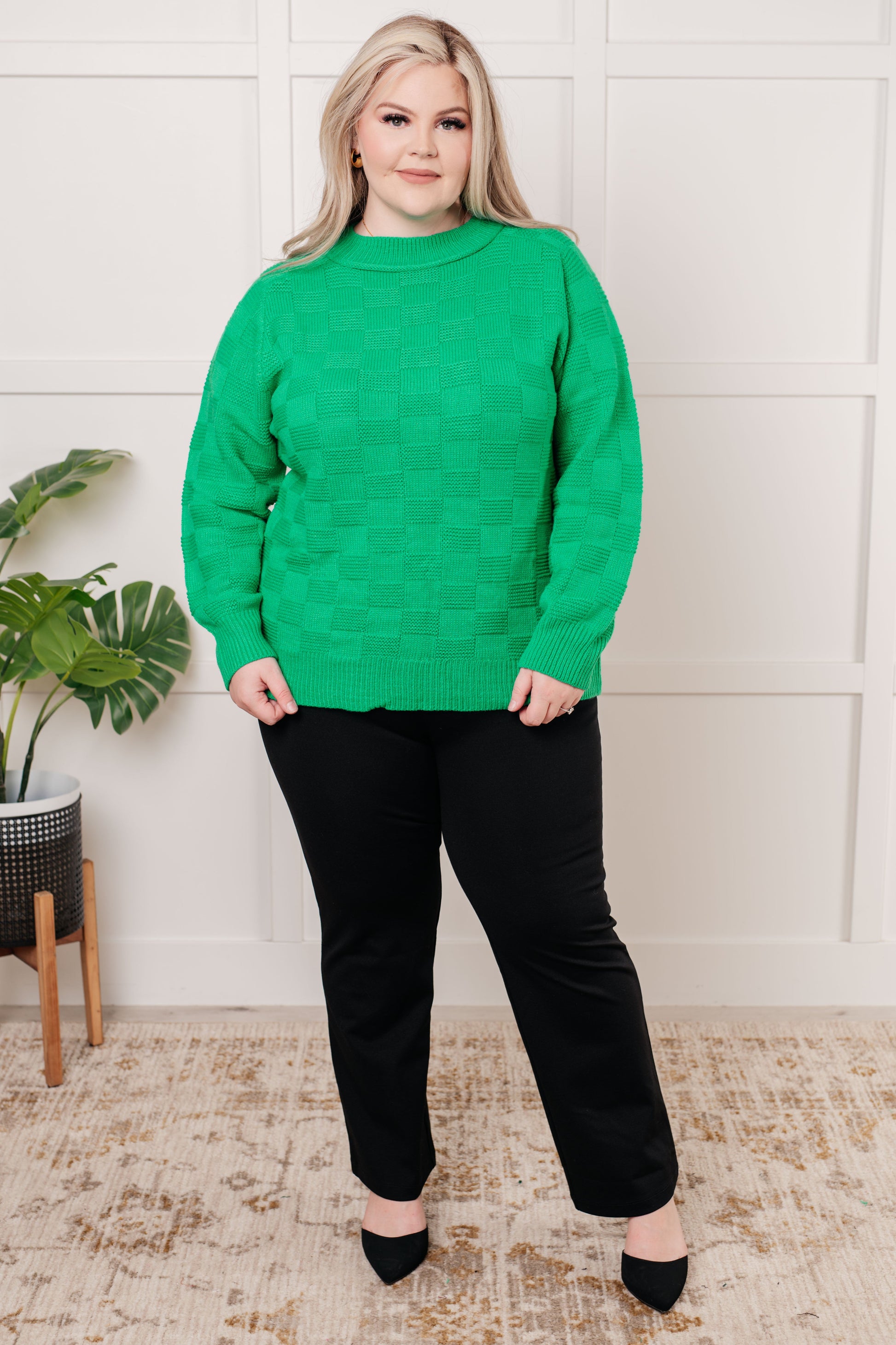 Green women's sweater with a monochromatic checker pattern, round ribbed neckline, long sleeves, and ribbed cuffs and hemline.