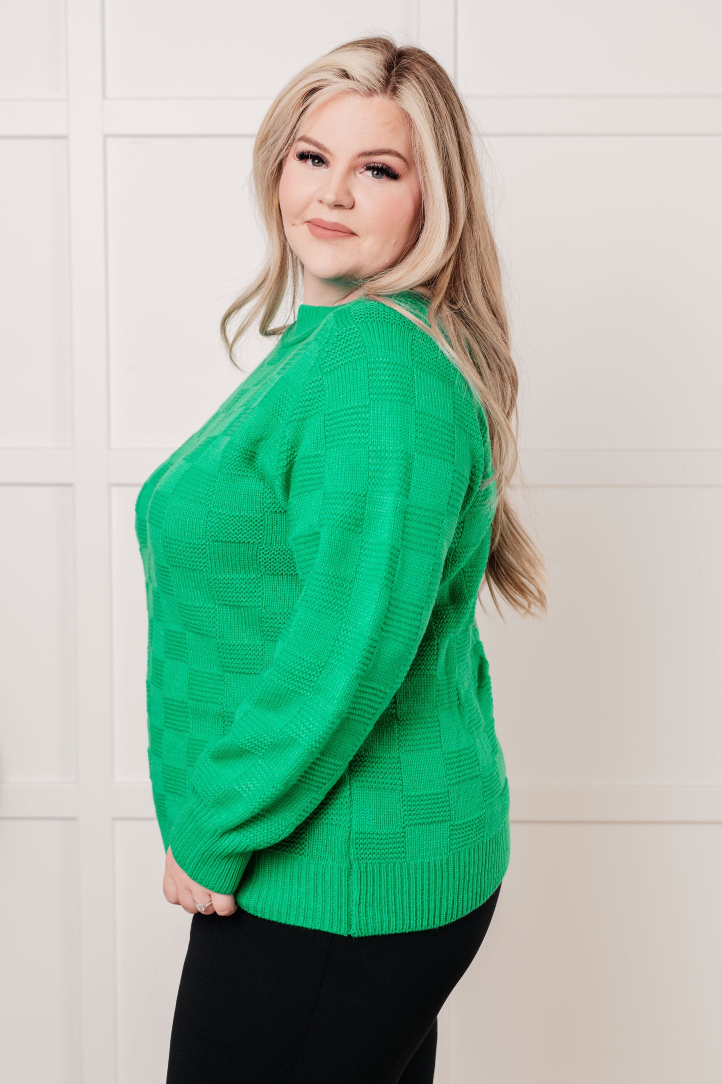 Green women's sweater with a monochromatic checker pattern, round ribbed neckline, long sleeves, and ribbed cuffs and hemline.