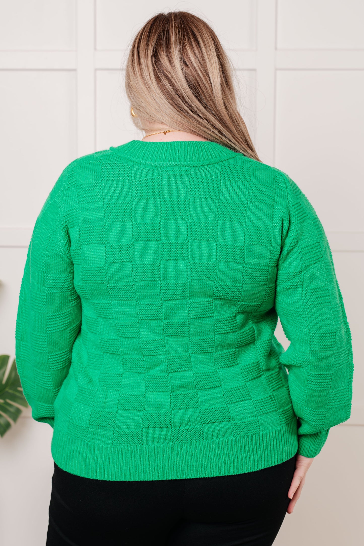 Green women's sweater with a monochromatic checker pattern, round ribbed neckline, long sleeves, and ribbed cuffs and hemline.