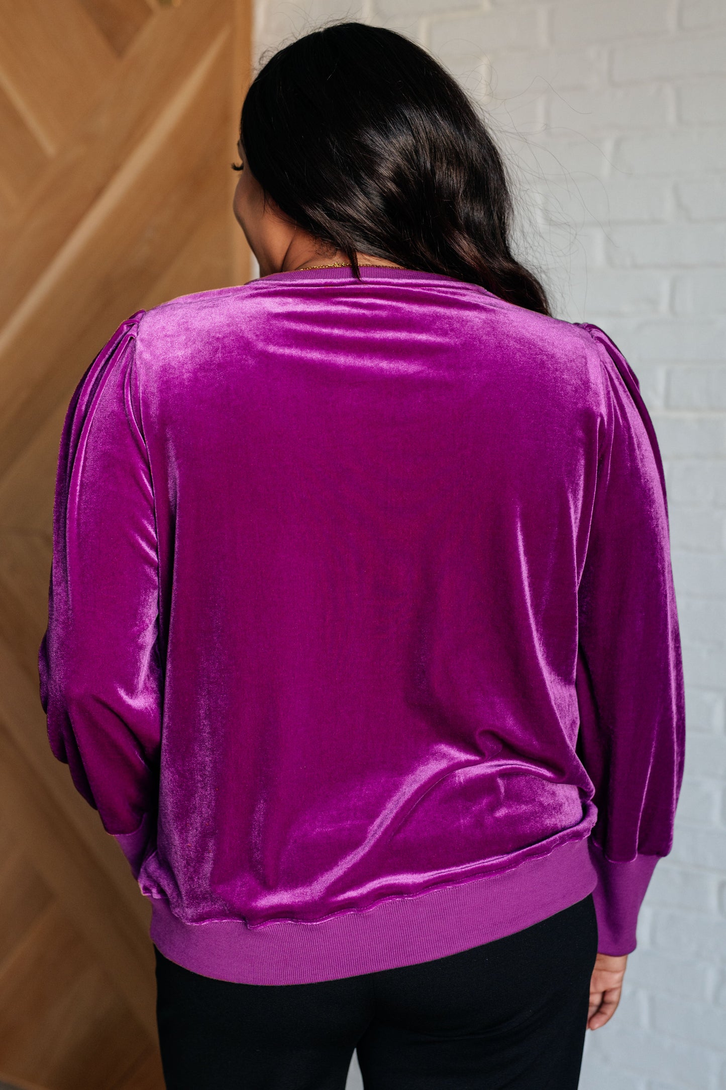 Magenta soft velour knit pullover with long balloon sleeves, gathered shoulders, and a banded round neckline. Features banded contrast cuffs and hemline.