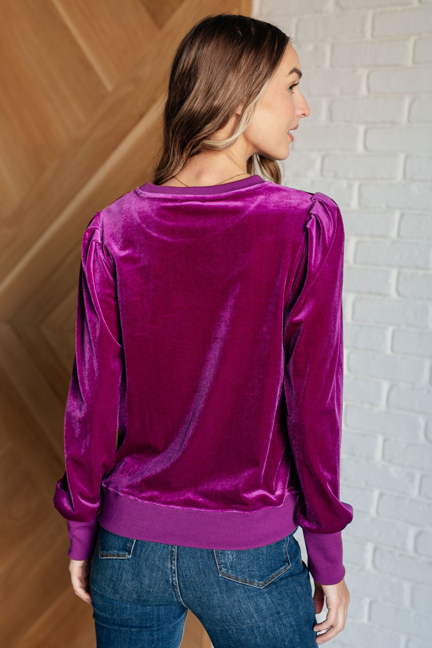 Magenta soft velour knit pullover with long balloon sleeves, gathered shoulders, and a banded round neckline. Features banded contrast cuffs and hemline.