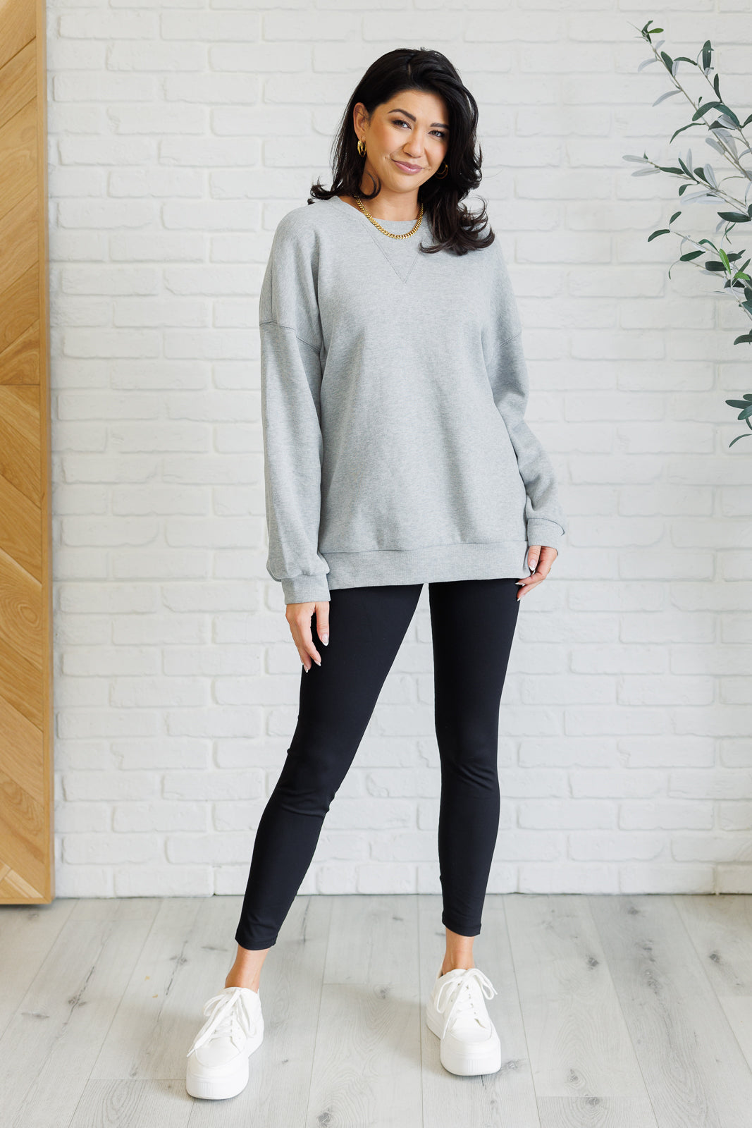 Oversized gray pullover in mid-weight knit with a banded crew neckline, drop shoulder long sleeves, banded cuffs and hemline, side slits, and back seam detail.