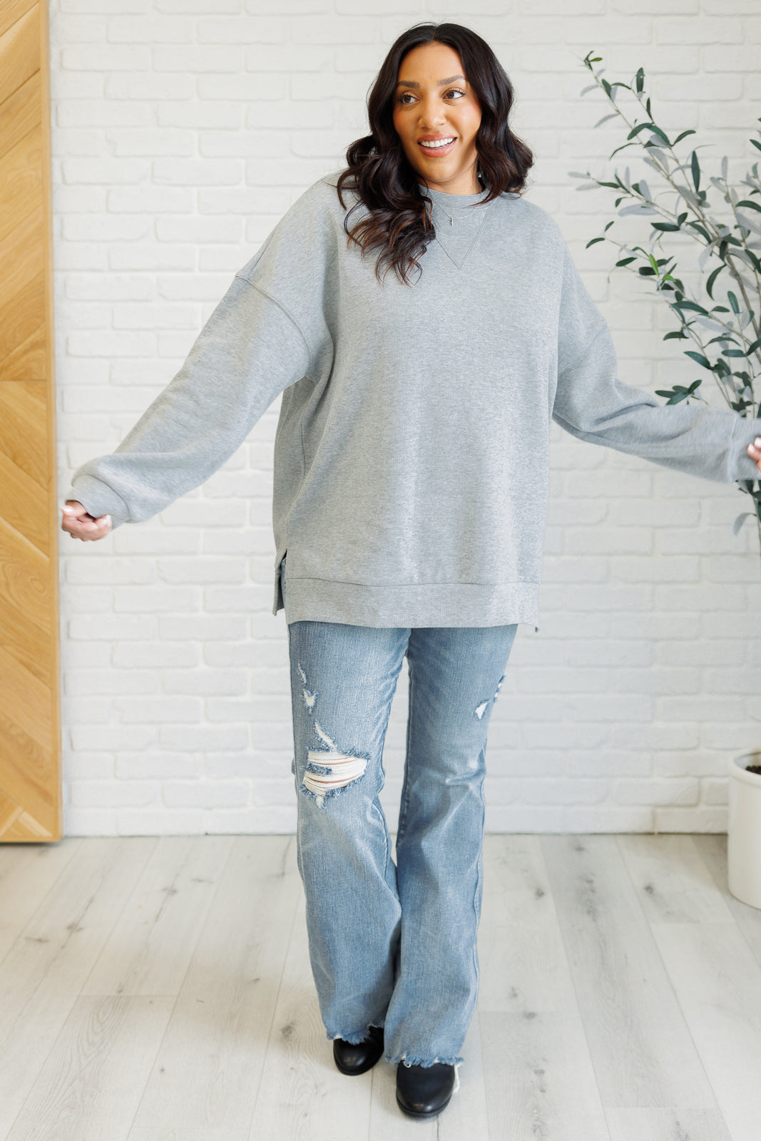 Oversized gray pullover in mid-weight knit with a banded crew neckline, drop shoulder long sleeves, banded cuffs and hemline, side slits, and back seam detail.