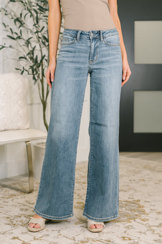 Model wearing Adrian Mid Rise Retro Wide Leg Jeans in medium wash with zipper fly.