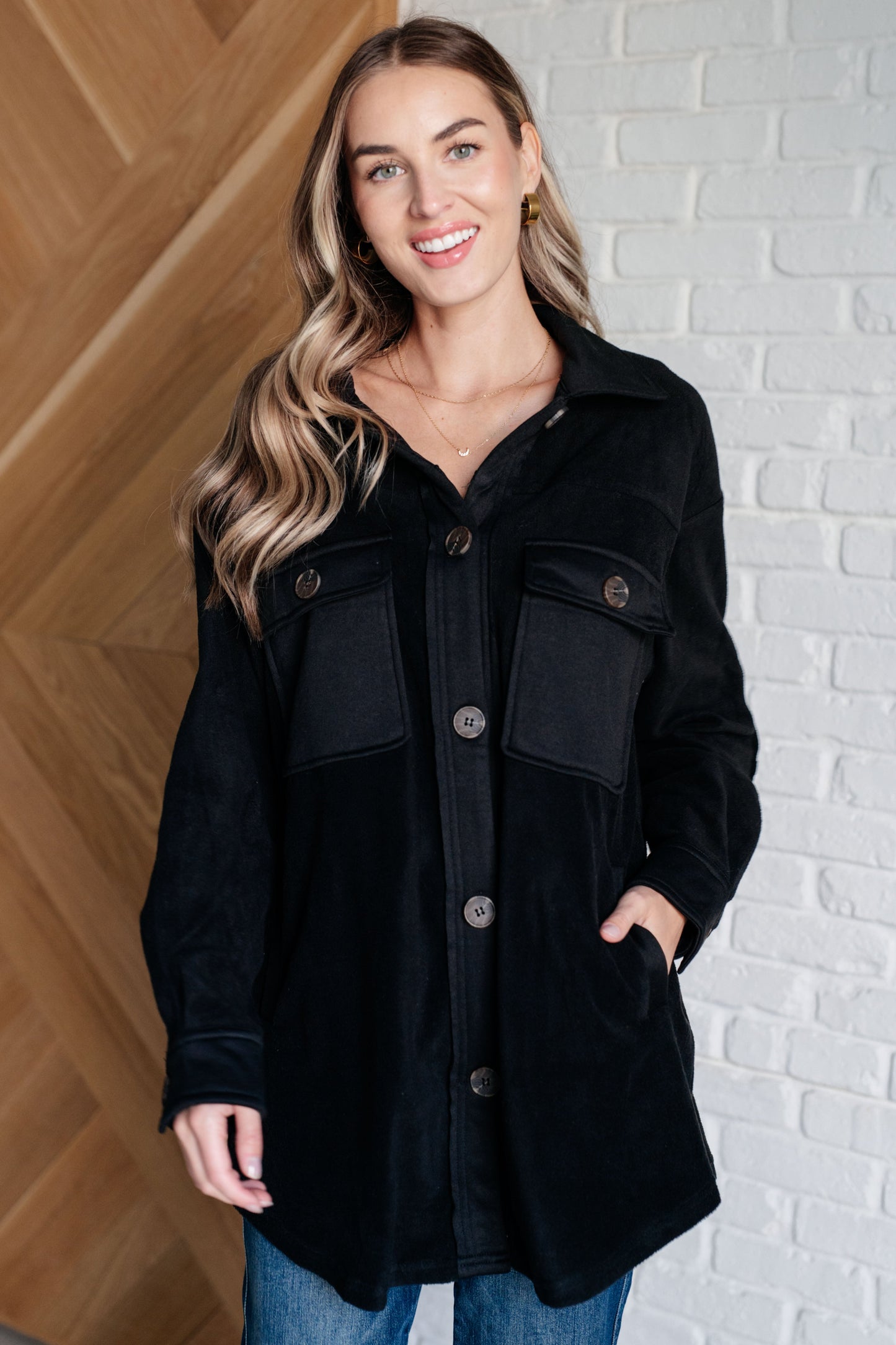 Model wearing Akeelah Fleece Jacket in black with collared neckline and button front.