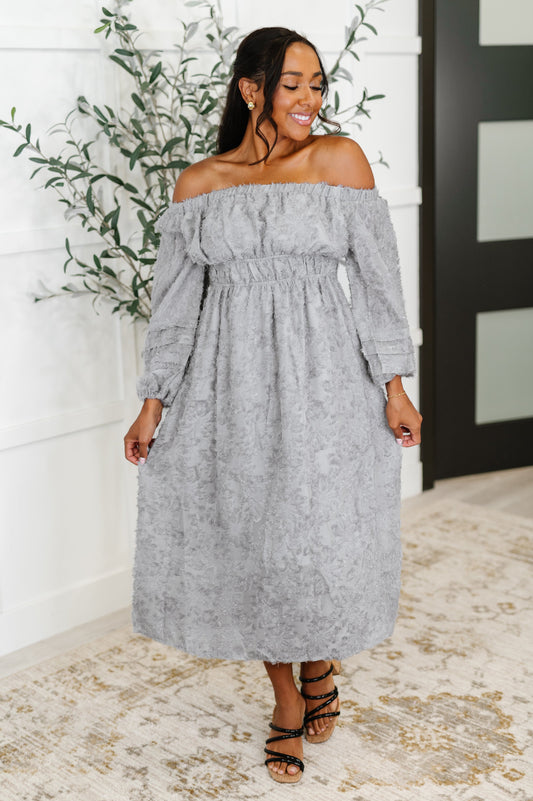 Full body front view of model in Janelle Off Shoulder Floral Chiffon Midi Dress in opal gray with lavender undertones, styled with sandals.