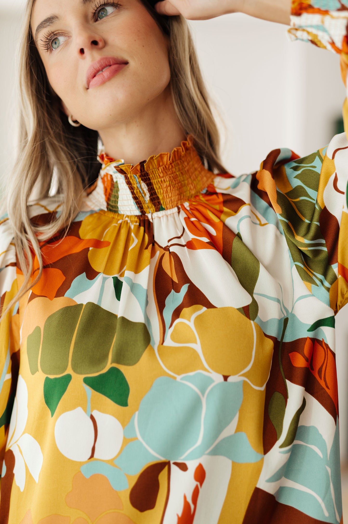 Front close-up of Dylan Mock Neck Blouse showing smocked neckline, button detail, and floral satin fabric