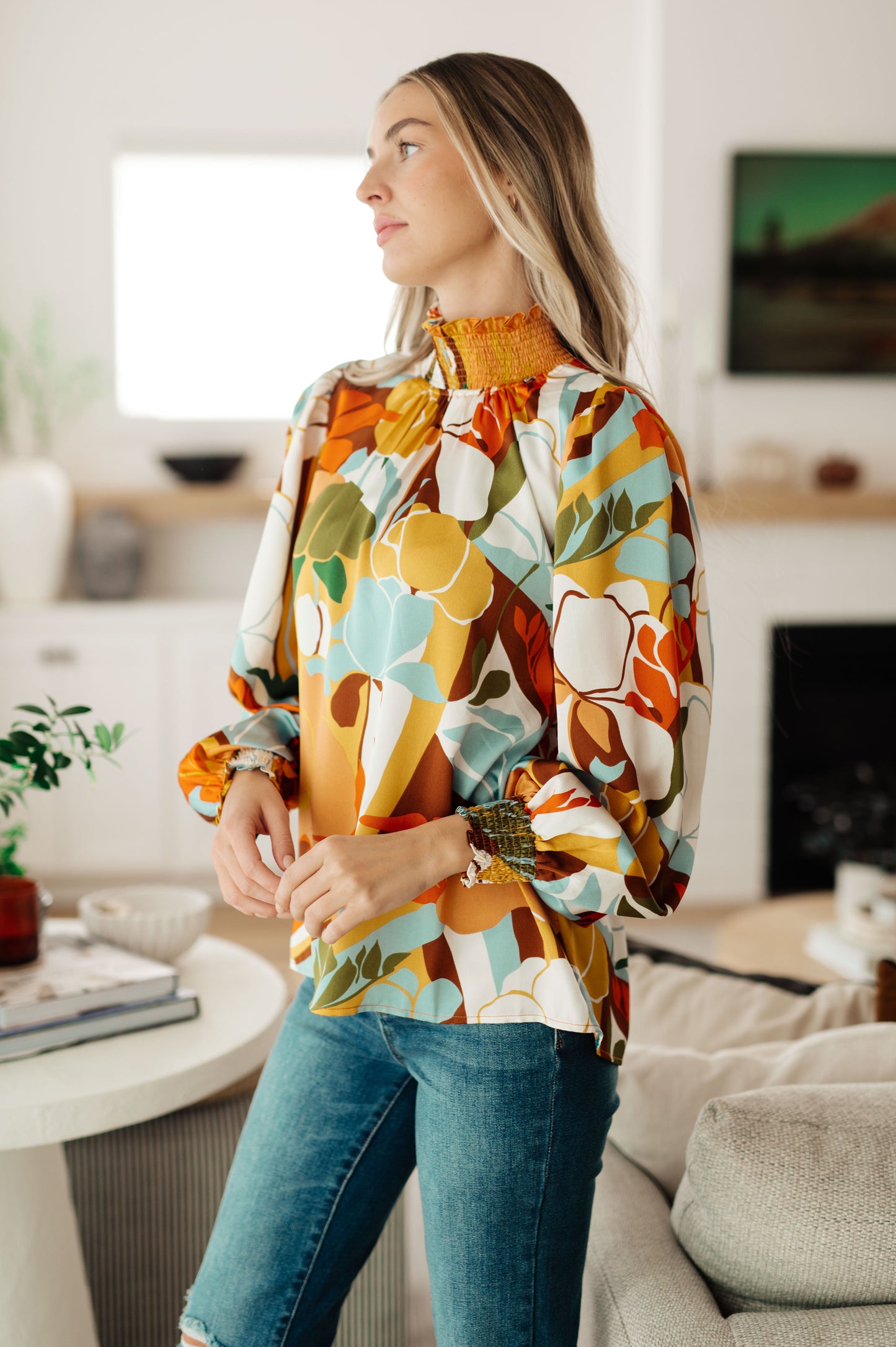 Side view of Dylan Mock Neck Blouse highlighting satin fabric, smocked cuff, and tangerine floral base