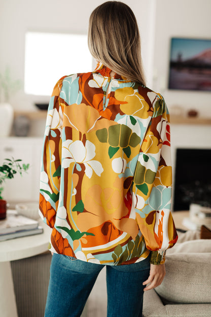 Back view of Dylan Mock Neck Blouse highlighting multi-colored floral satin fabric with button closure