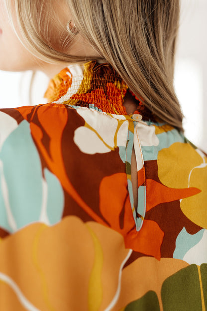 Close-up back of Dylan Mock Neck Blouse showing button closure and smocked neckline in floral satin fabric