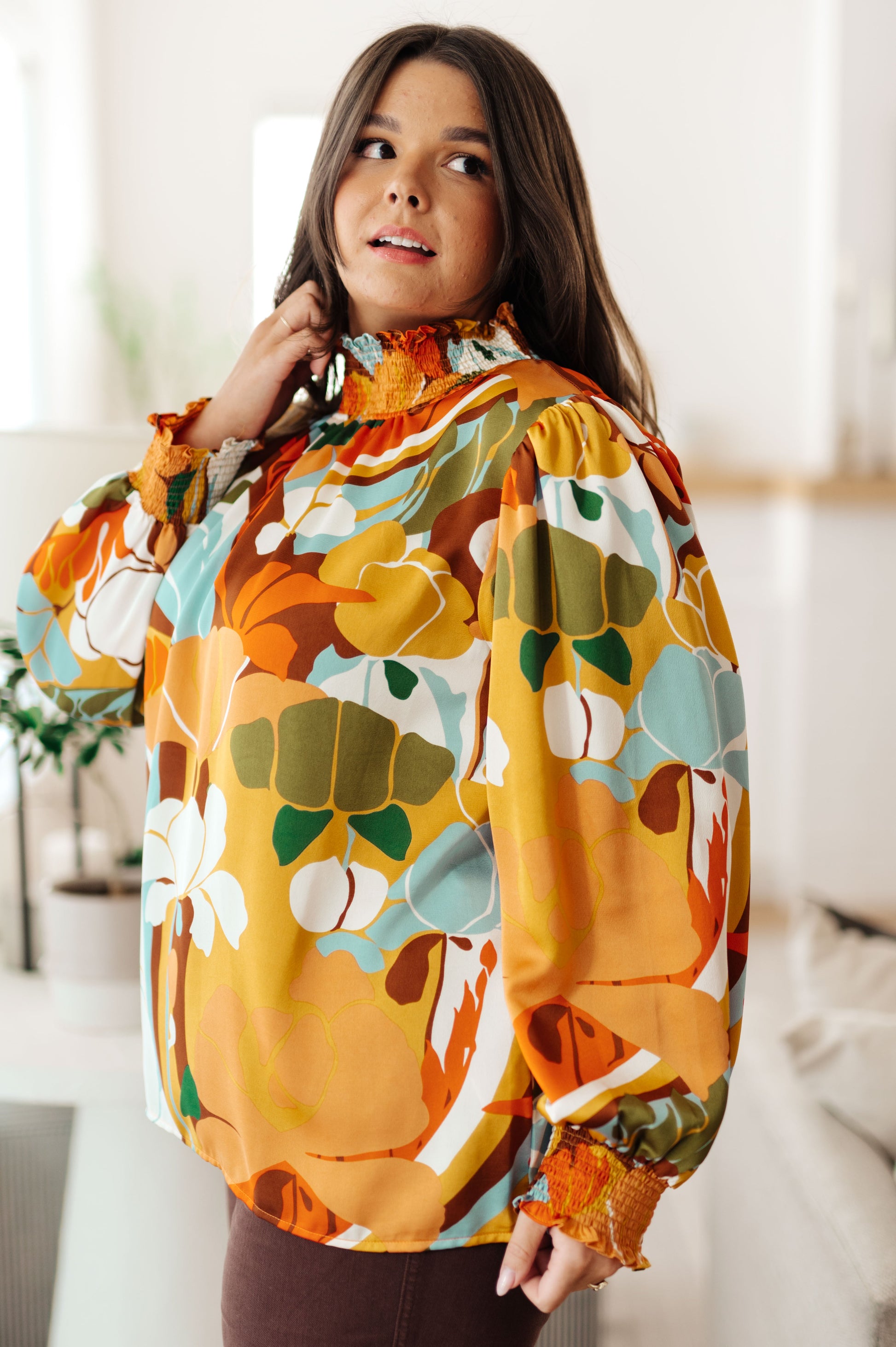 Plus size side view of Dylan Mock Neck Blouse showing flowy satin fit with tangerine floral print and cuffs