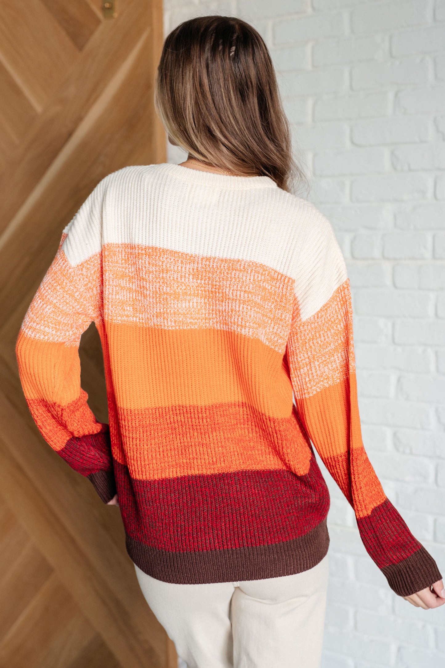 Women's oversized color block sweater with a banded ribbed round neckline, long drop-shoulder sleeves, and sweater knit fabric in white, peach, orange, red, and brown tones.