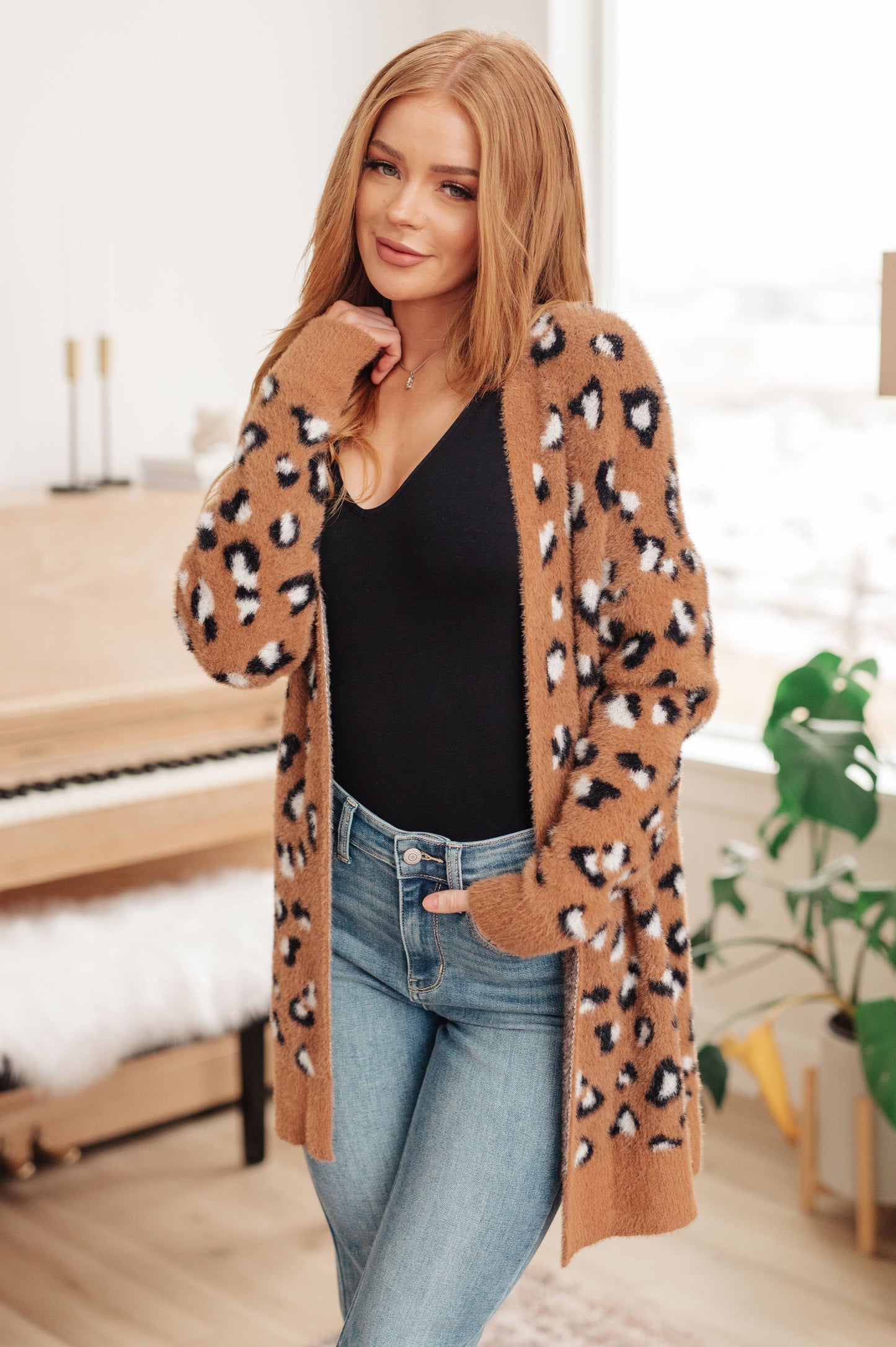 A women's longline cardigan in brown with a leopard print pattern, made from soft eyelash sweater knit fabric. Features an open front design, dropped shoulders, and long sleeves.