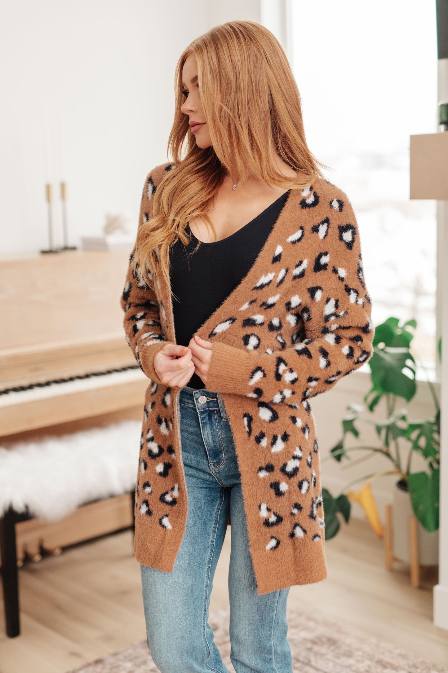 A women's longline cardigan in brown with a leopard print pattern, made from soft eyelash sweater knit fabric. Features an open front design, dropped shoulders, and long sleeves.