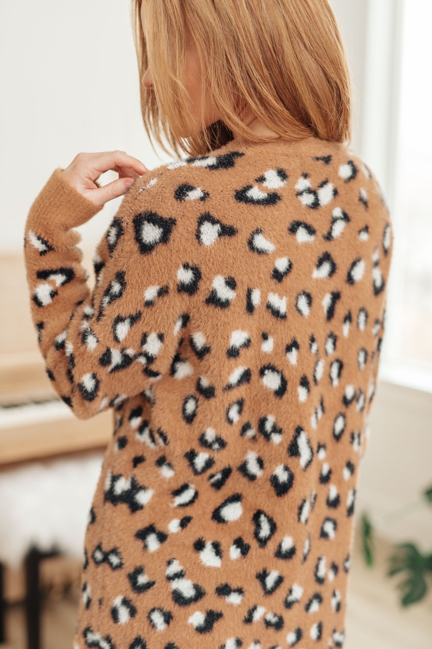 A women's longline cardigan in brown with a leopard print pattern, made from soft eyelash sweater knit fabric. Features an open front design, dropped shoulders, and long sleeves.