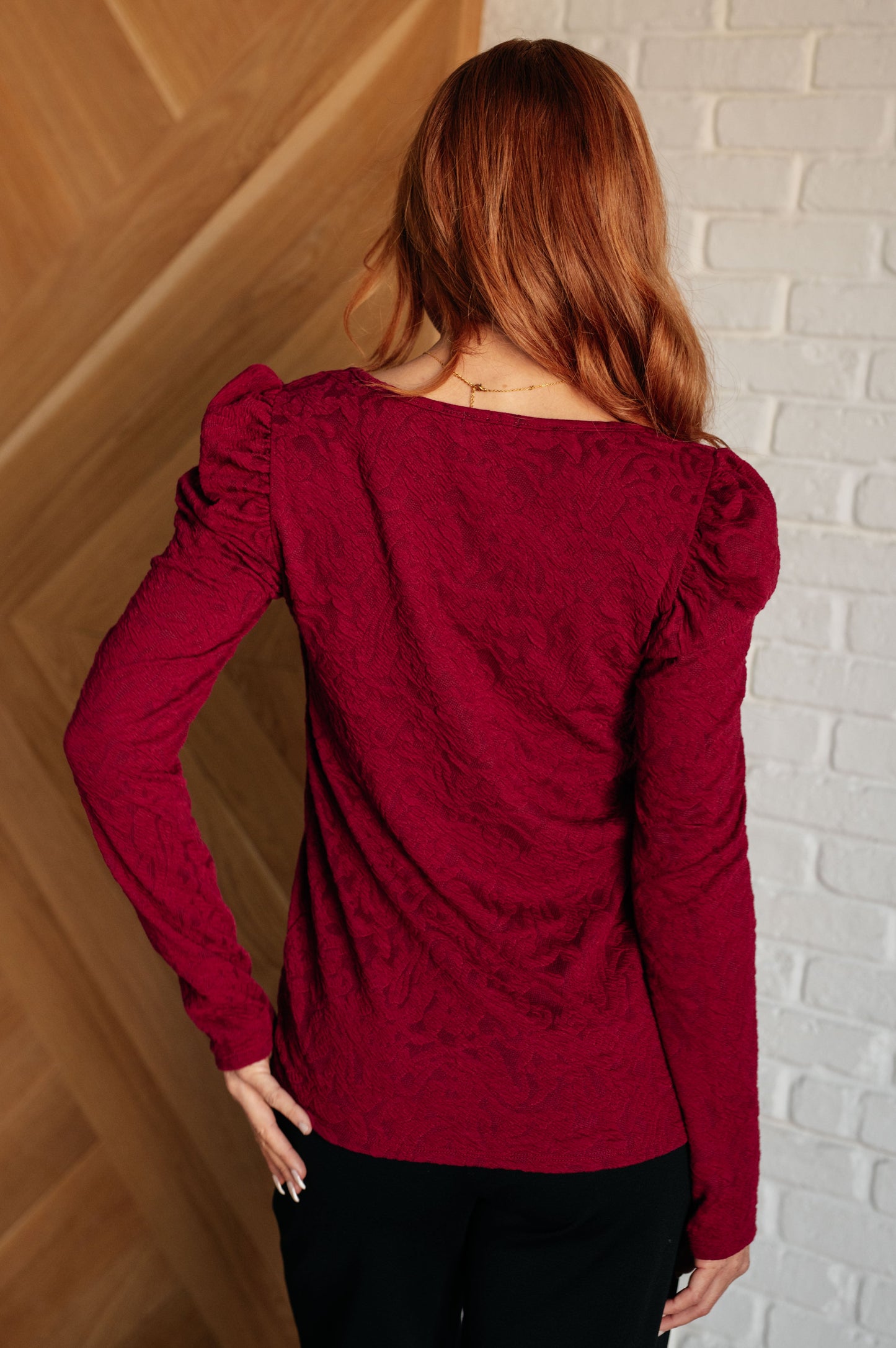 Wine-colored top with a sweetheart neckline and long puff sleeves, made from luxurious jacquard knit fabric.