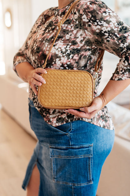 Woman wearing Golden Hour Crossbody over shoulder with woven vegan leather design and gold hardware.
