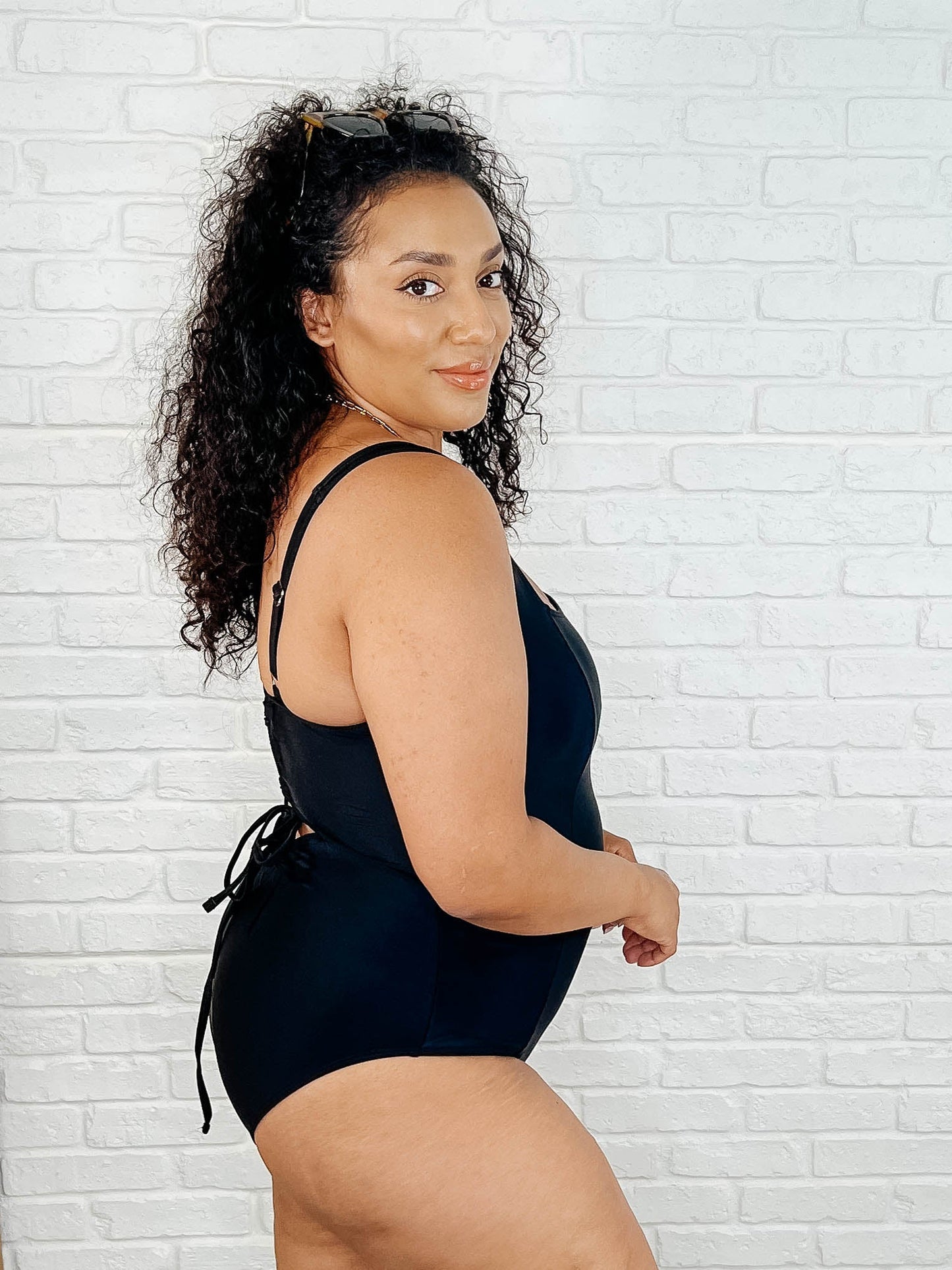 Side view of plus size Barcelona swimsuit in black with lace-up back and flattering cheeky coverage.
