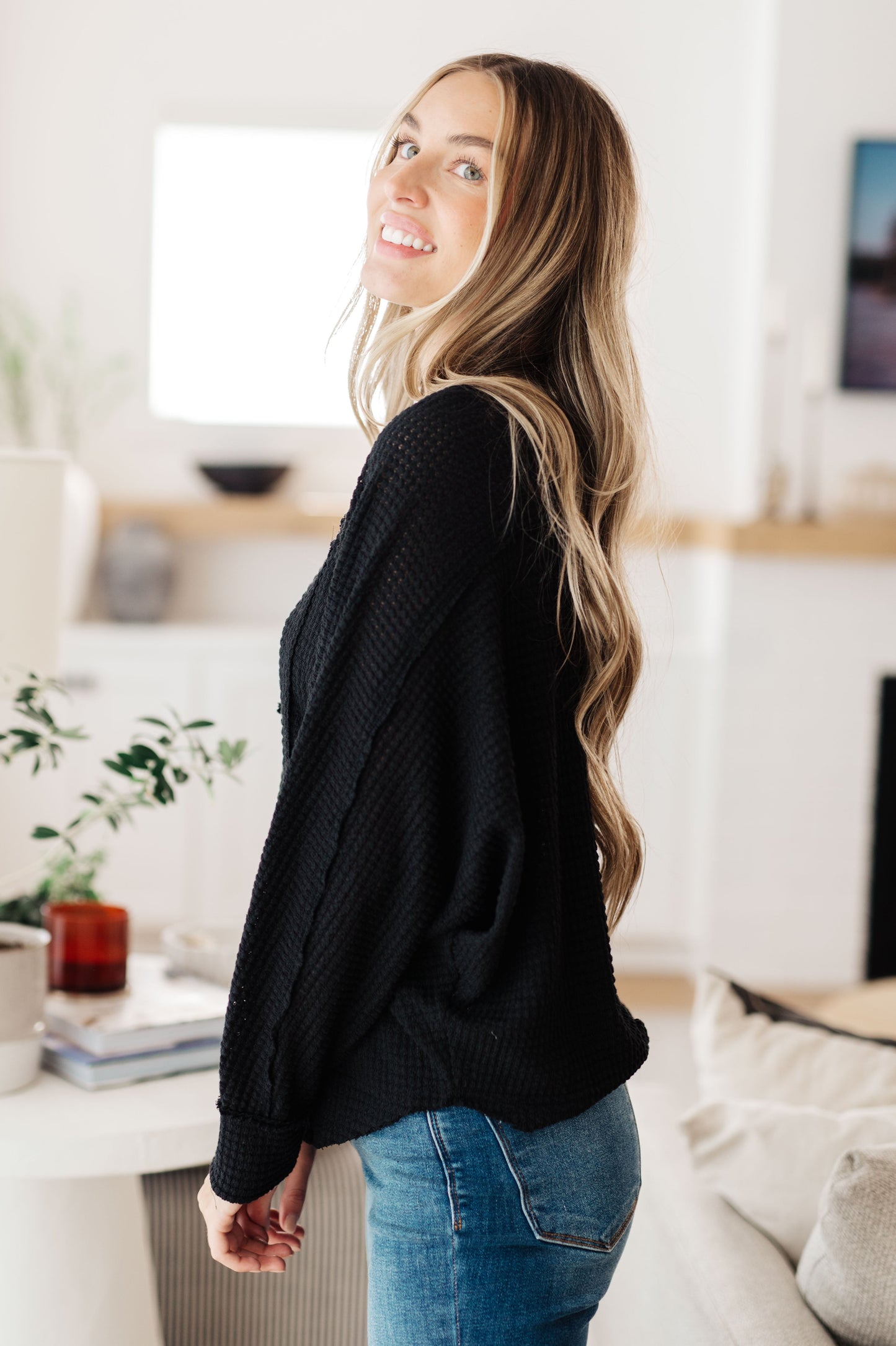 Side view of Bea Black Henley Top in soft waffle knit with long sleeves and relaxed fit.