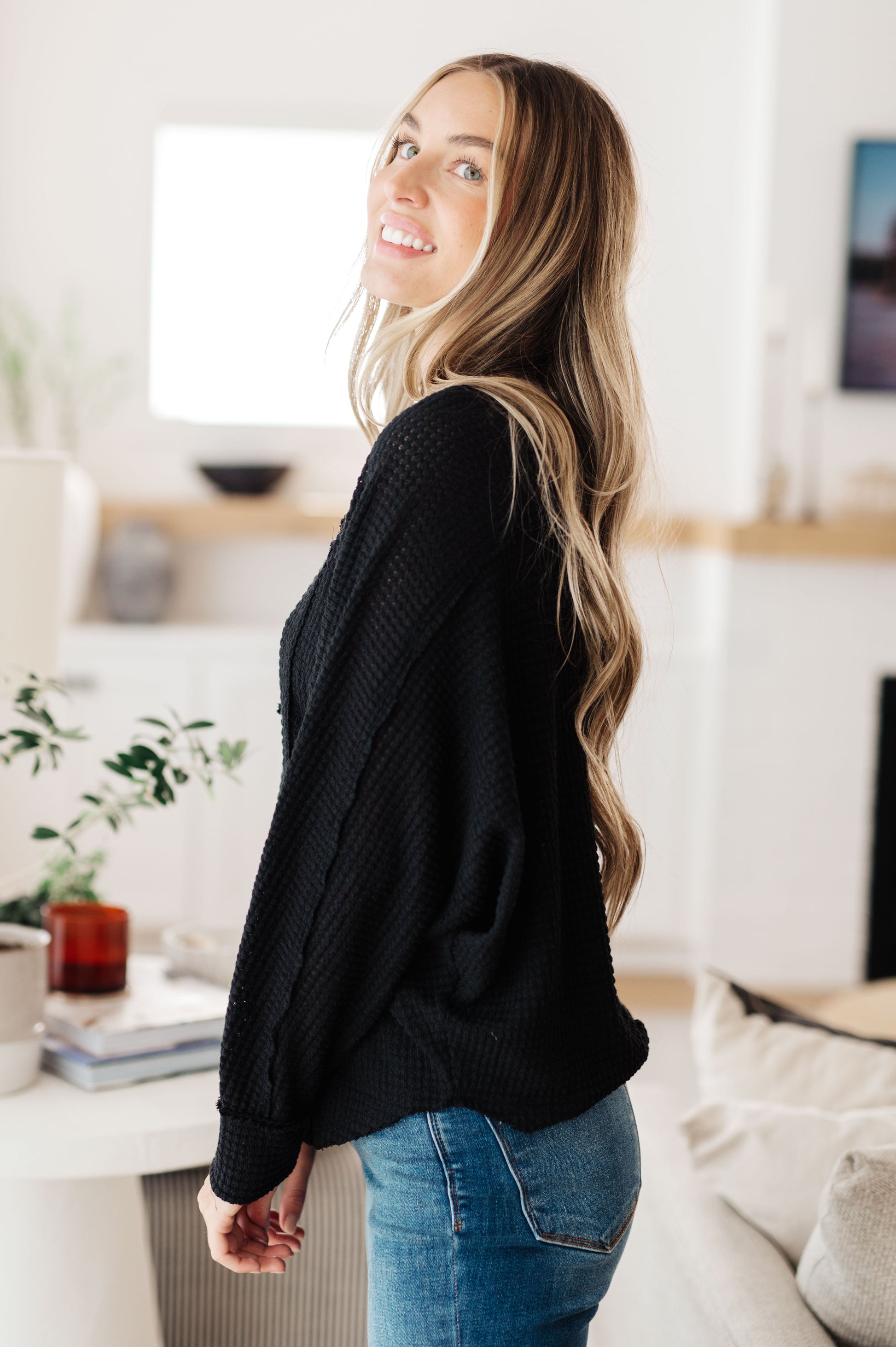 Side view of Bea Black Henley Top in soft waffle knit with long sleeves and relaxed fit.