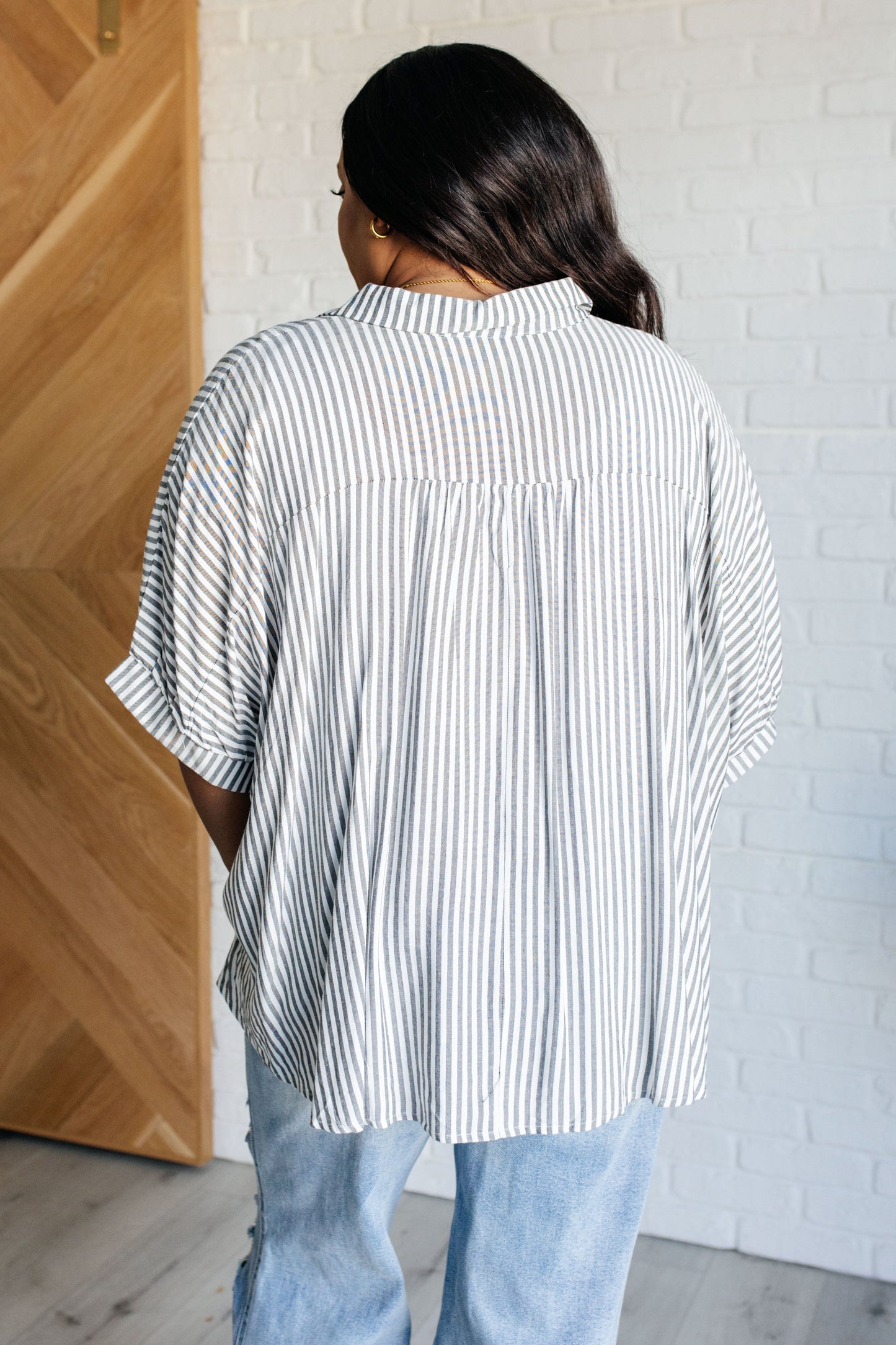 Back view of women's plus sIze button-up shirt in  white with black stripes, featuring a collared neckline, short dolman sleeves, banded cuffs, button closure, and a scooped hemline.