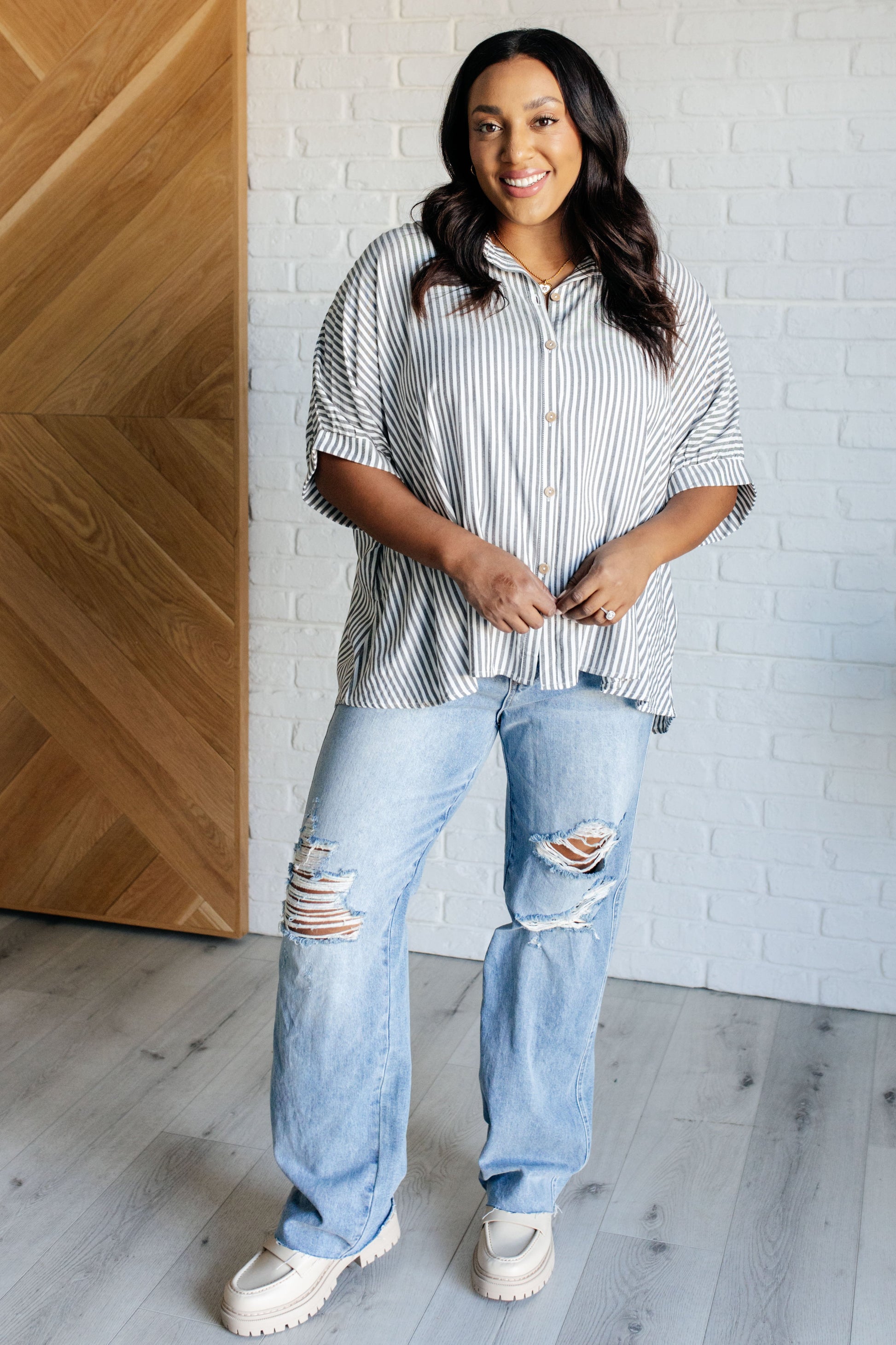 Women's plus size button-up shirt in  white with black stripes, featuring a collared neckline, short dolman sleeves, banded cuffs, button closure, and a scooped hemline with an oversized fit.