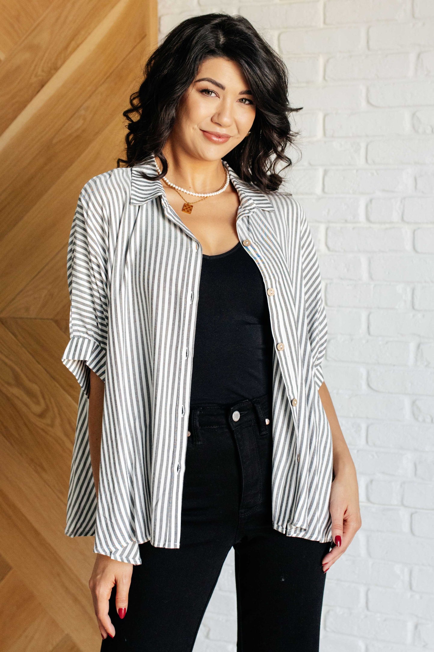 Women's oversized button-up shirt in  white with black stripes, featuring a collared neckline, short dolman sleeves, banded cuffs, button closure, and a scooped hemline.