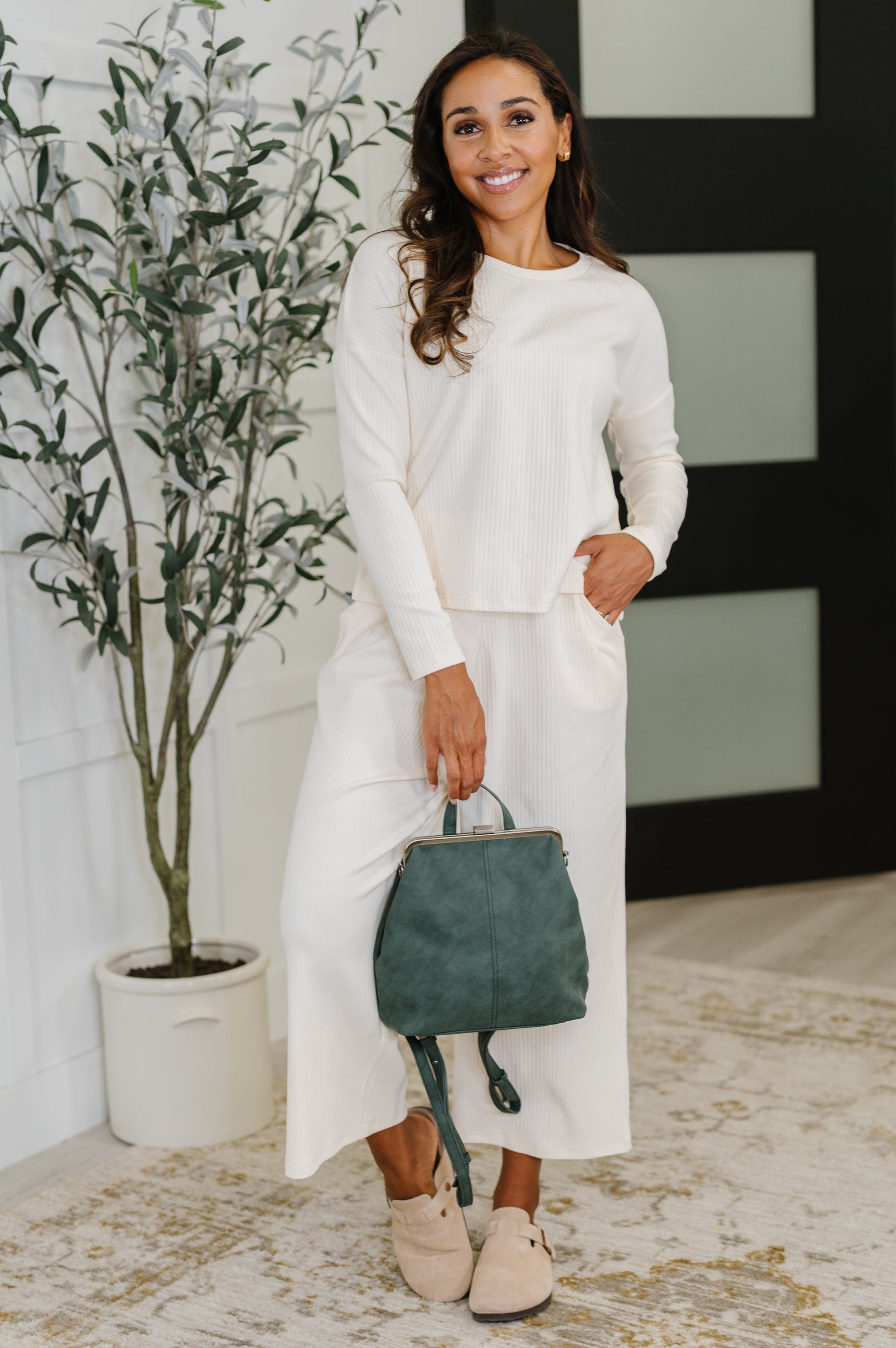 Model holding Bridget Backpack in Peacock, highlighting compact size and chic design.