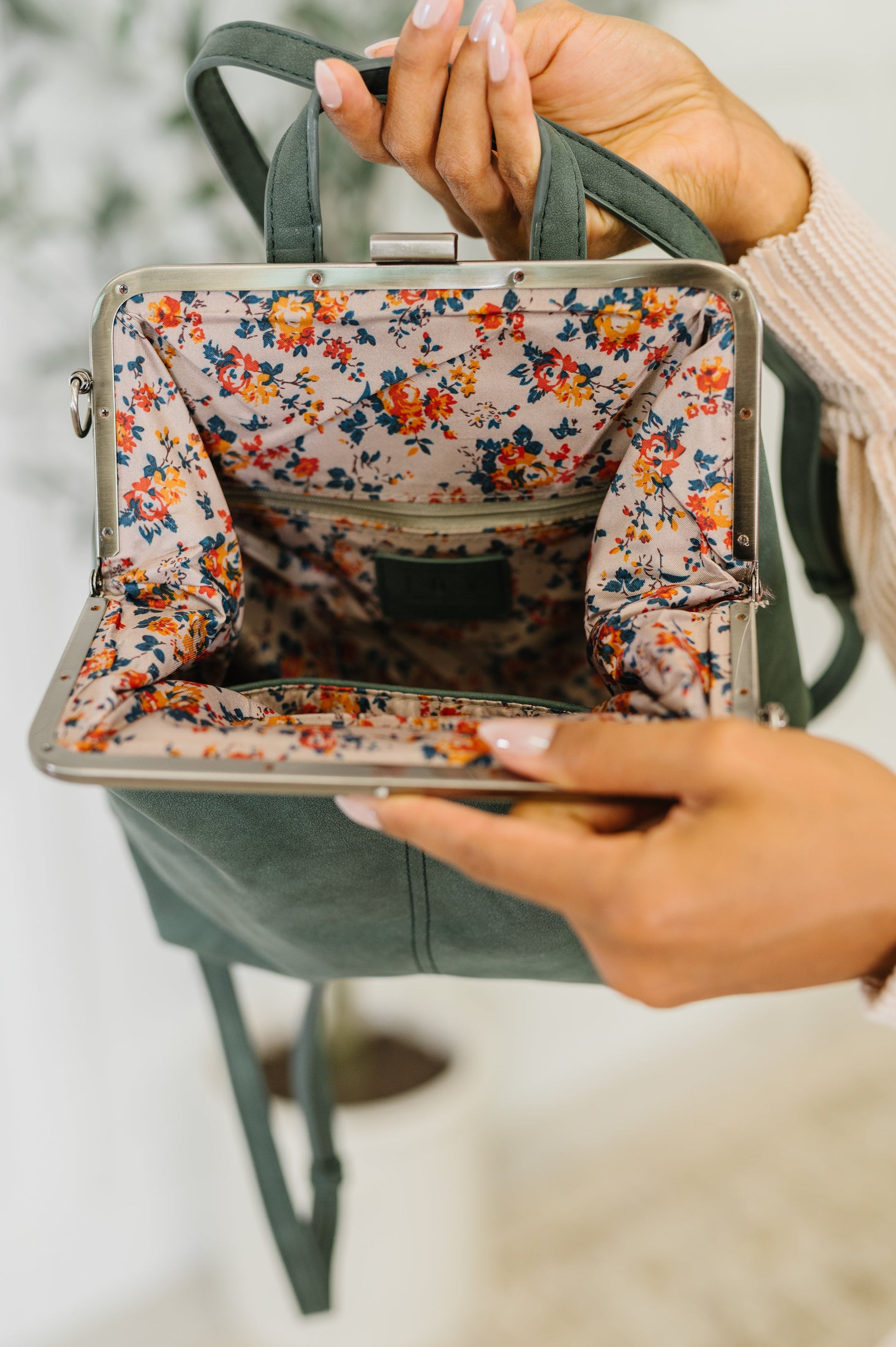 Model showing inside of Bridget Backpack in Peacock with floral lining and zip pocket.
