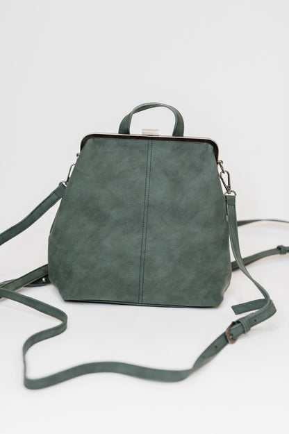 Bridget Backpack in Peacock, vegan leather with brass clasp closure, displayed on flat surface.