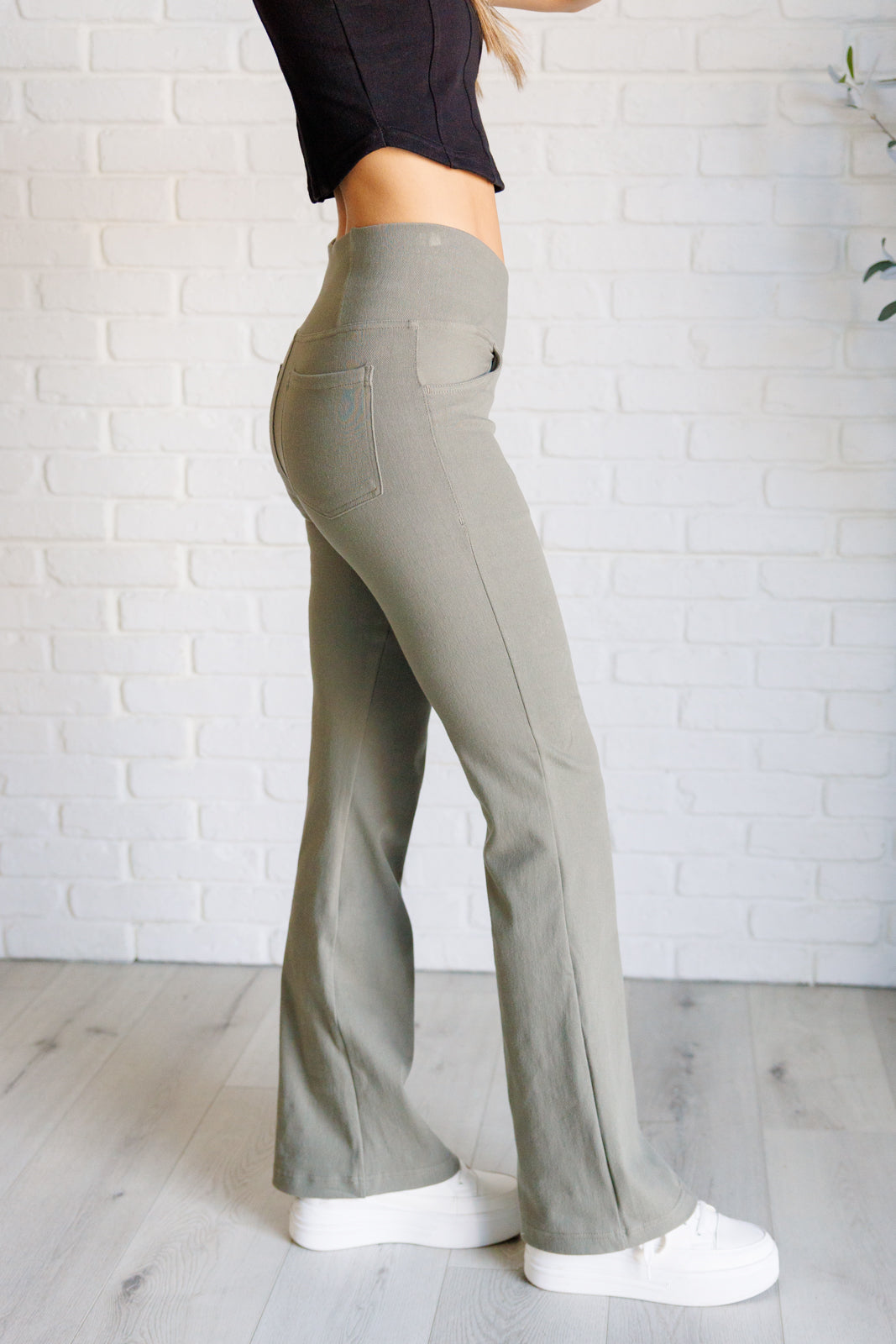 Twill Flared Crossover Waist Pants in dusty olive with a high V-waistline, medium-stretch fabric, flared legs, and functional front and back pockets.