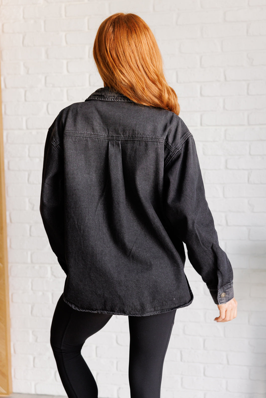 Back of oversized denim shacket in a washed blue fabric with a button front and snap gusseted pockets. Perfect for layering over casual outfits.