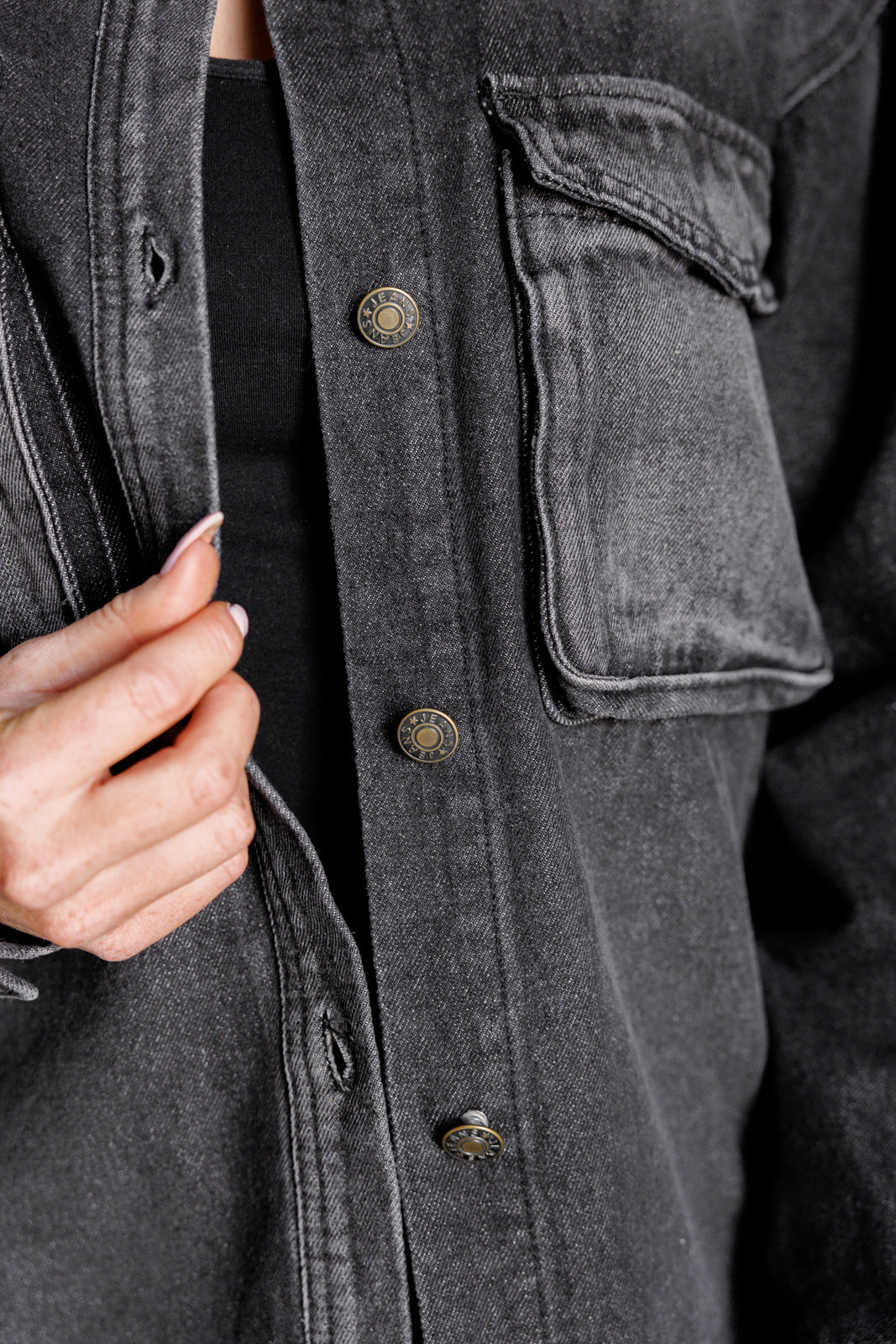 Close-up view of the Fia Washed Denim Shacket, showing its textured washed fabric, snap pocket detail, and button front.