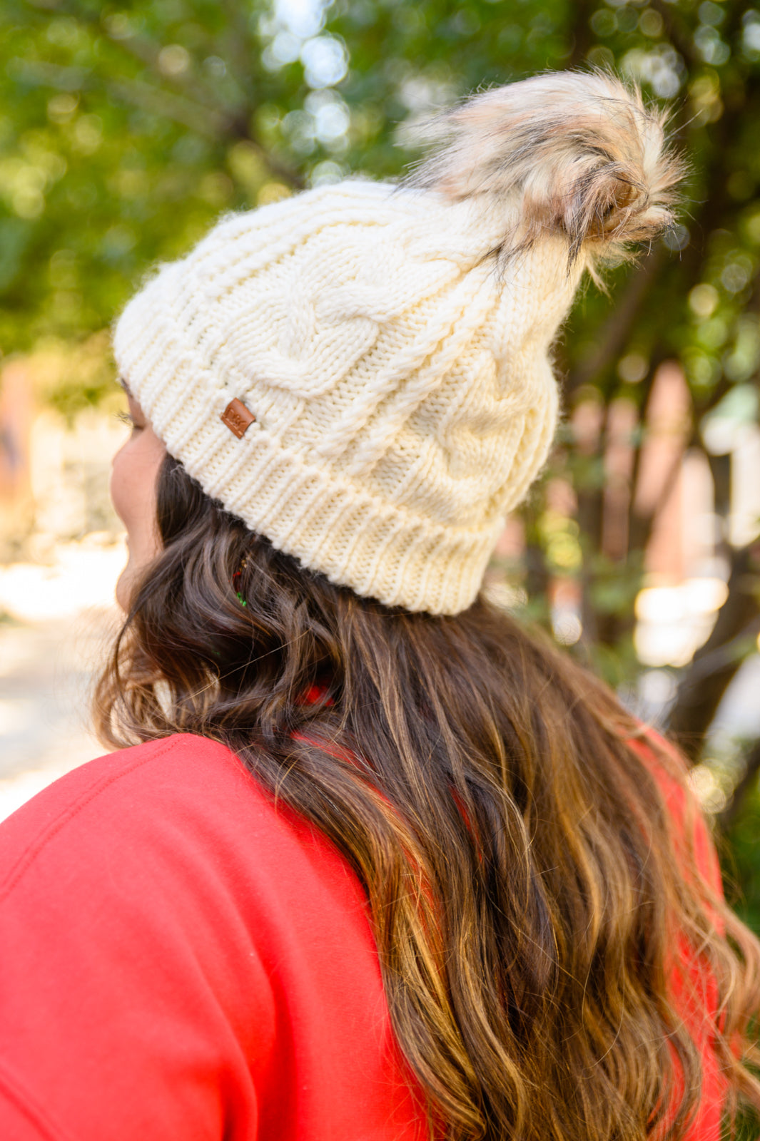 Ivory cable knit beanie with a pom top, cuffed hem, and fuzzy lining for warmth.