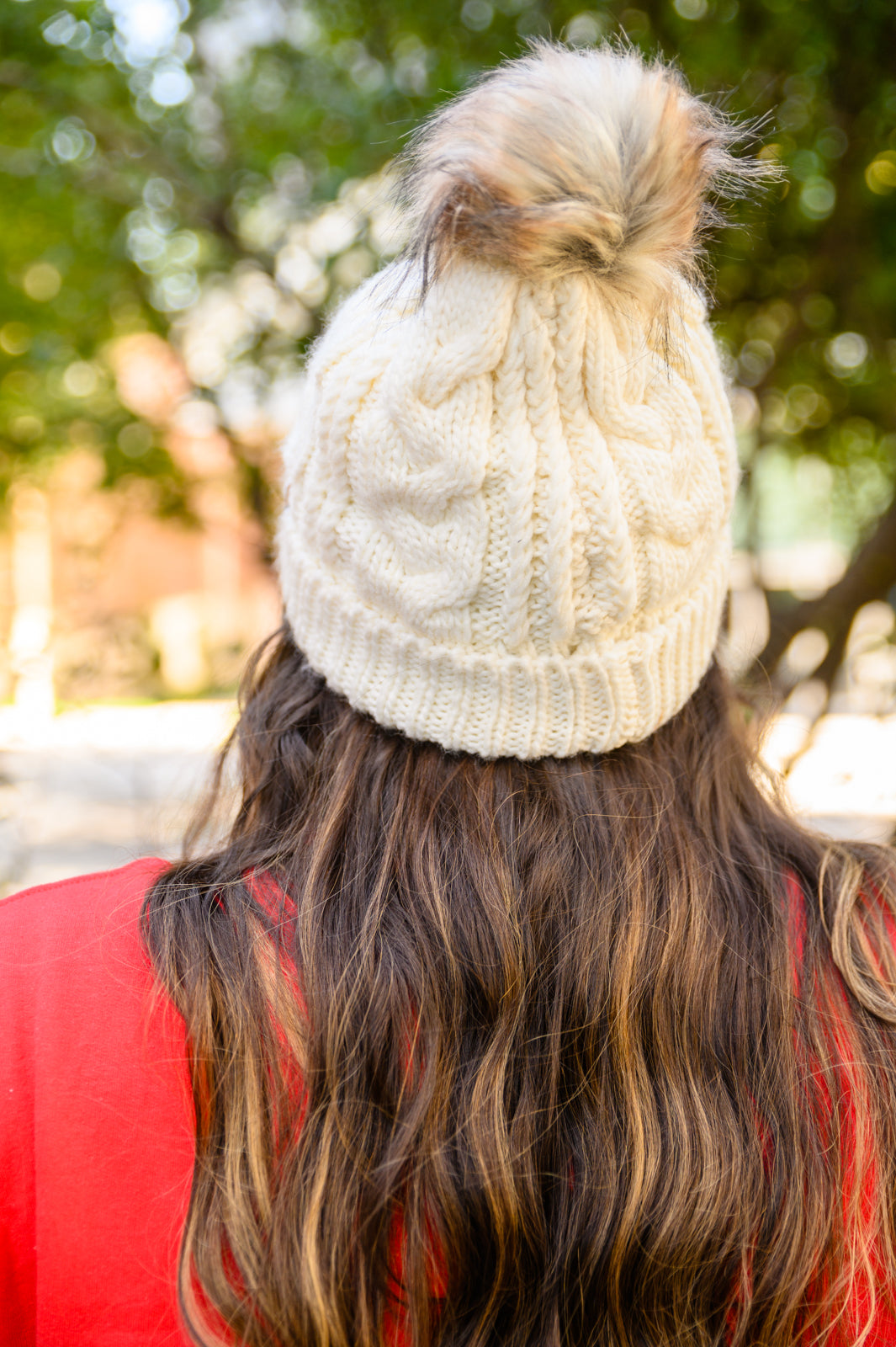 Ivory cable knit beanie with a pom top, cuffed hem, and fuzzy lining for warmth.