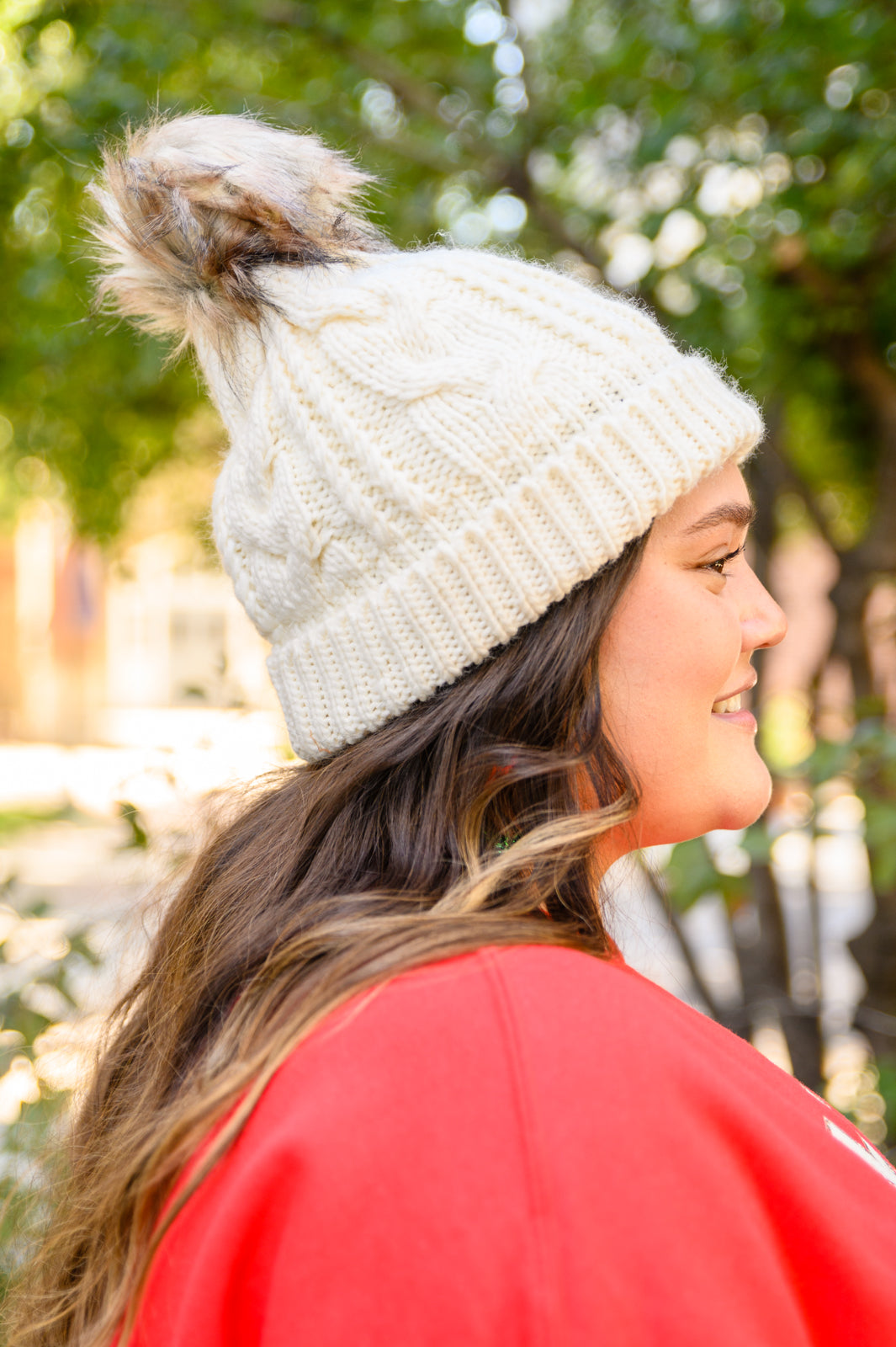 Ivory cable knit beanie with a pom top, cuffed hem, and fuzzy lining for warmth.