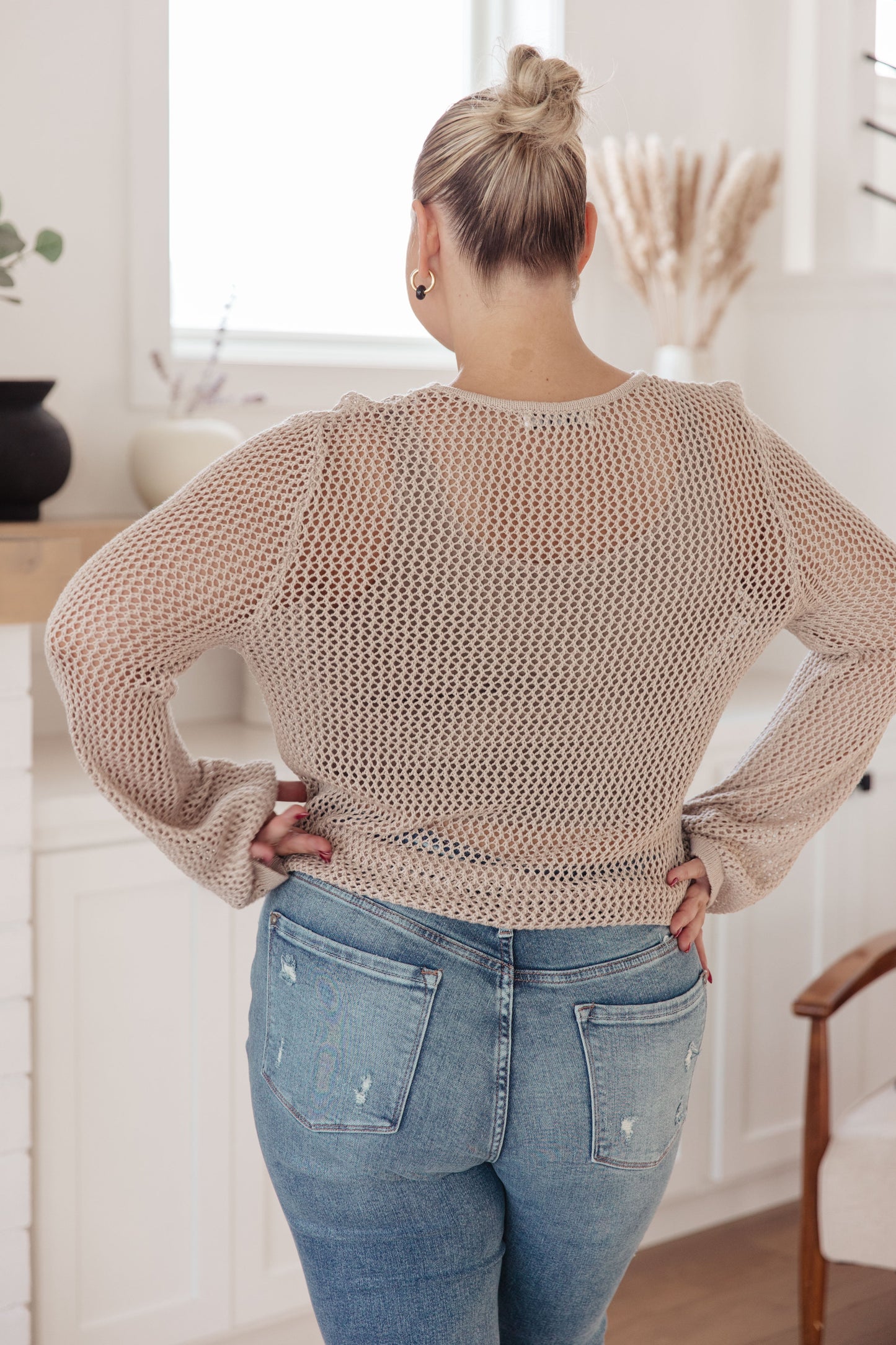 Women's sweater knit top with sheer open knit design, round neckline, and long sleeves.