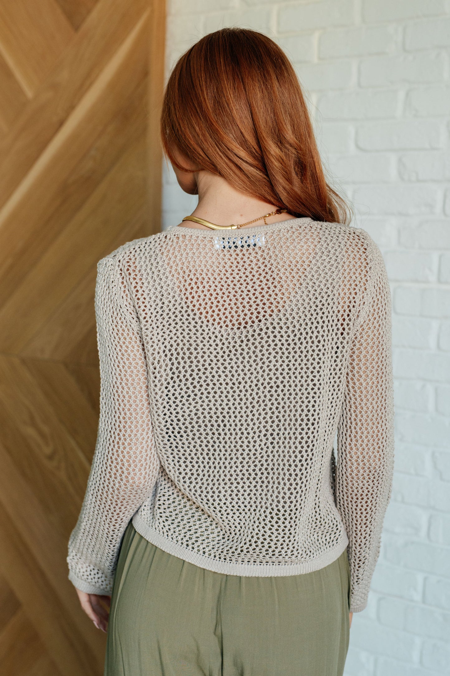 Women's sweater knit top with sheer open knit design, round neckline, and long sleeves.