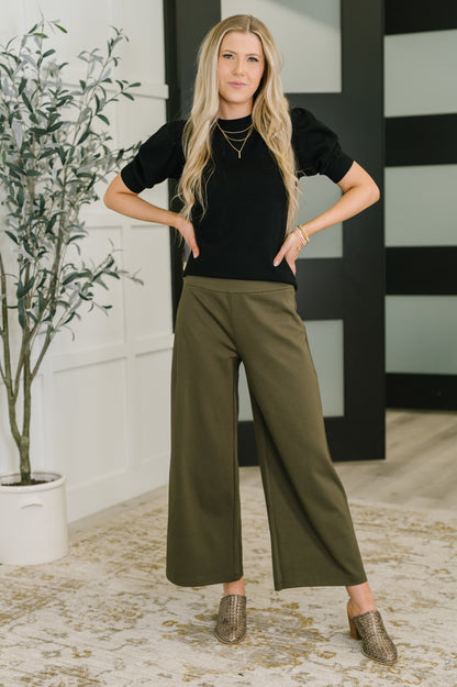 Model wearing Giselle Puff Sleeve Blouse in Black, full outfit view with ribbed hem.