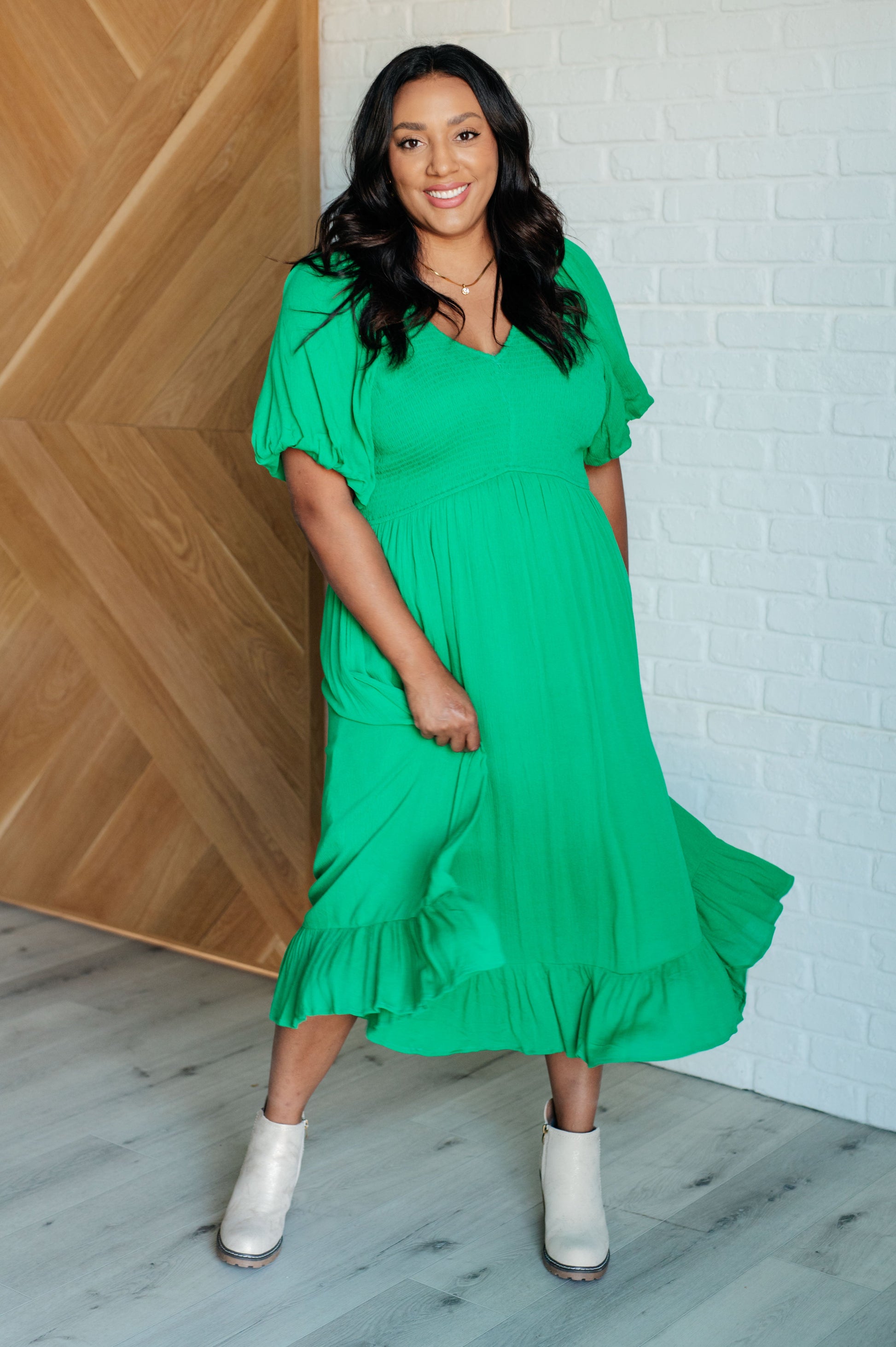 Green smocked dress with a V-neckline, short balloon sleeves, and a ruffled hemline.