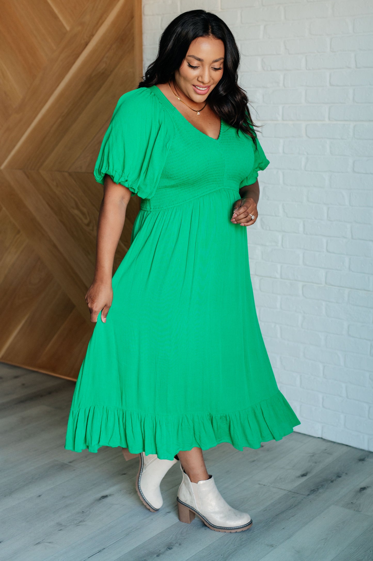 Green smocked dress with a V-neckline, short balloon sleeves, and a ruffled hemline.