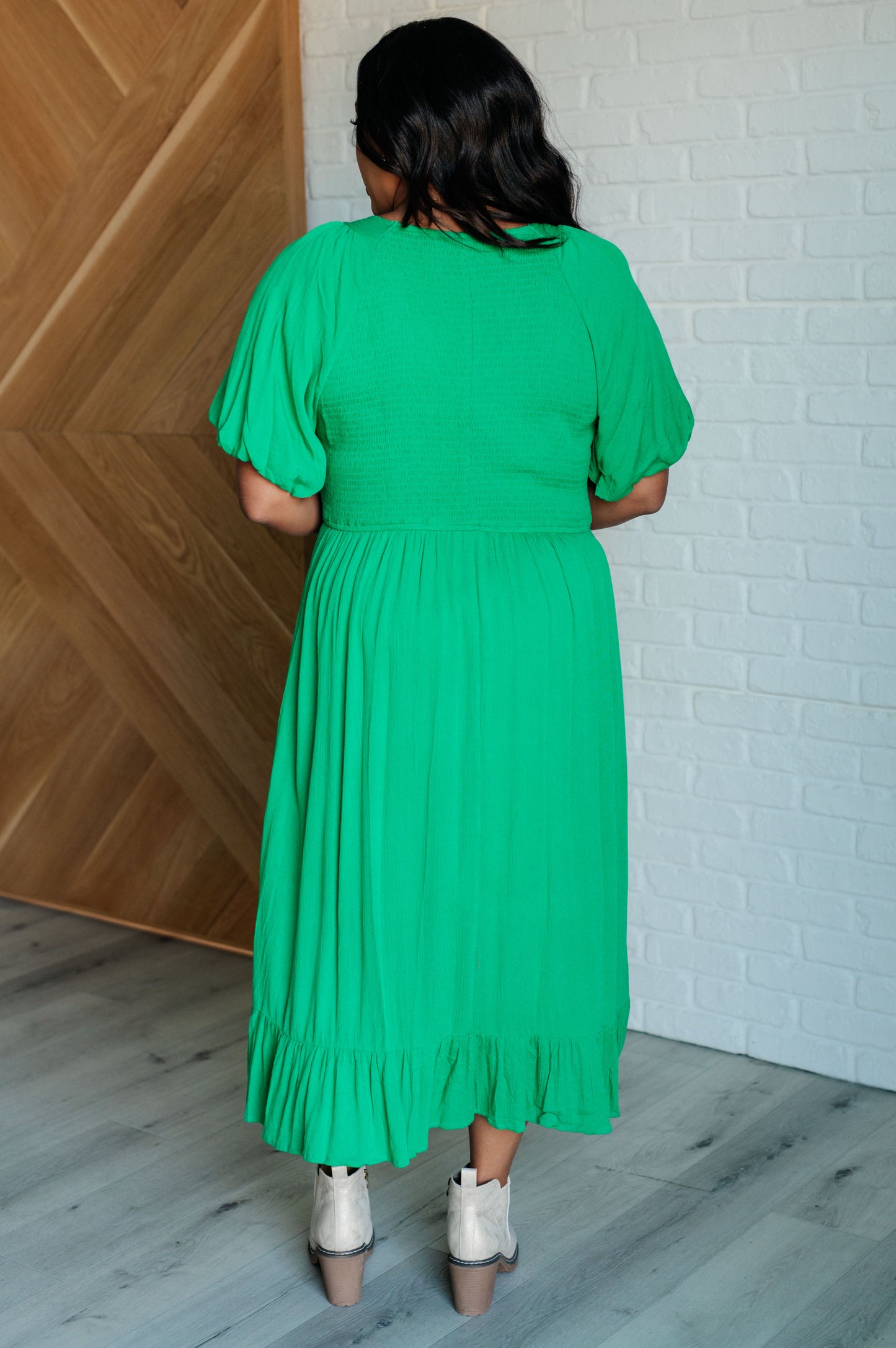 Green smocked dress with a V-neckline, short balloon sleeves, and a ruffled hemline.