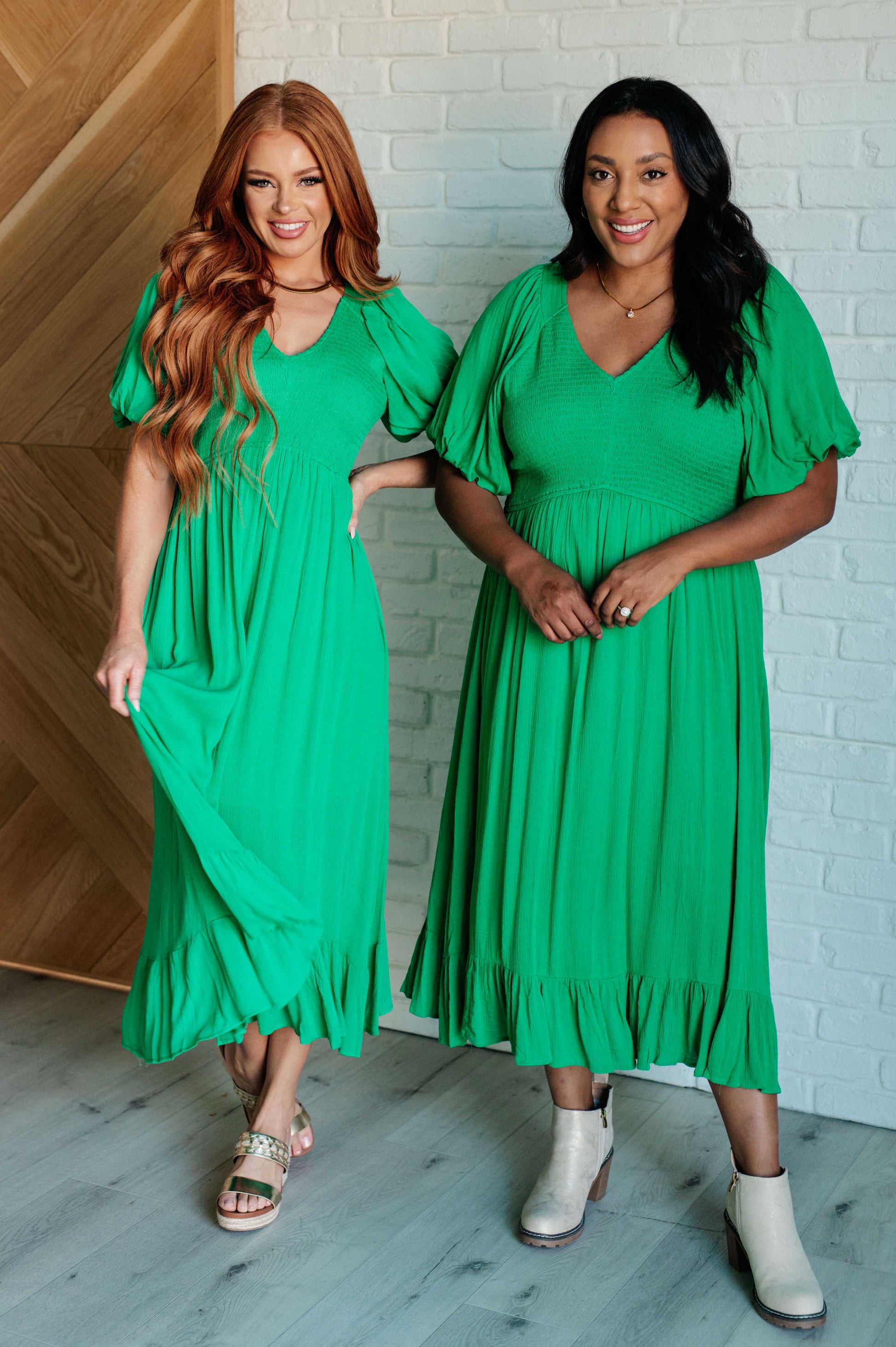 Green smocked dress with a V-neckline, short balloon sleeves, and a ruffled hemline.