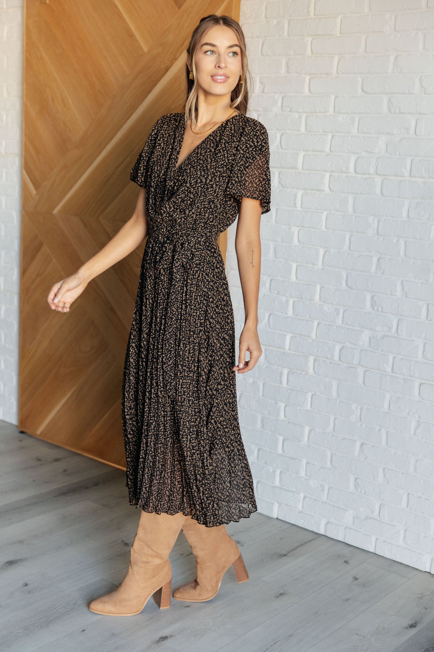 Black floral V-neck surplice midi dress with short flutter sleeves, elastic waistline with tie, and pleated chiffon fabric. Fully lined.