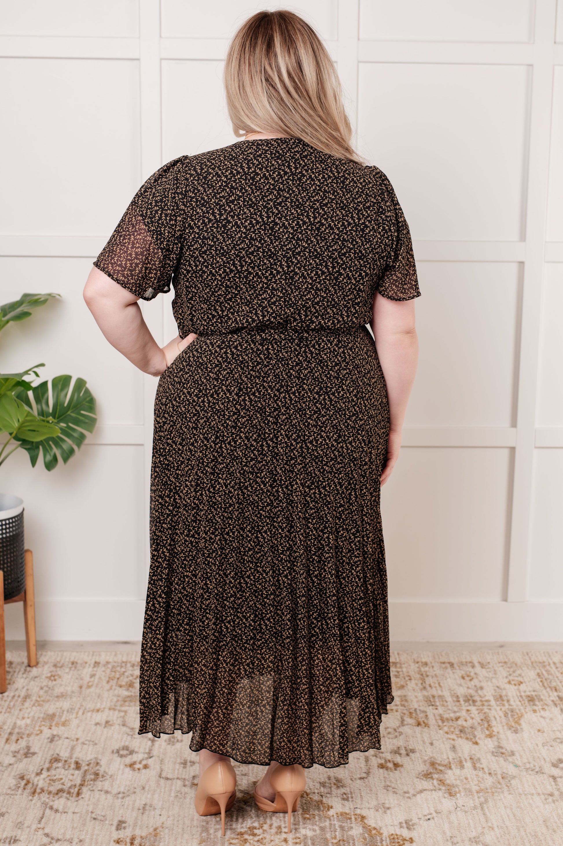 Black floral V-neck surplice midi dress with short flutter sleeves, elastic waistline with tie, and pleated chiffon fabric. Fully lined.