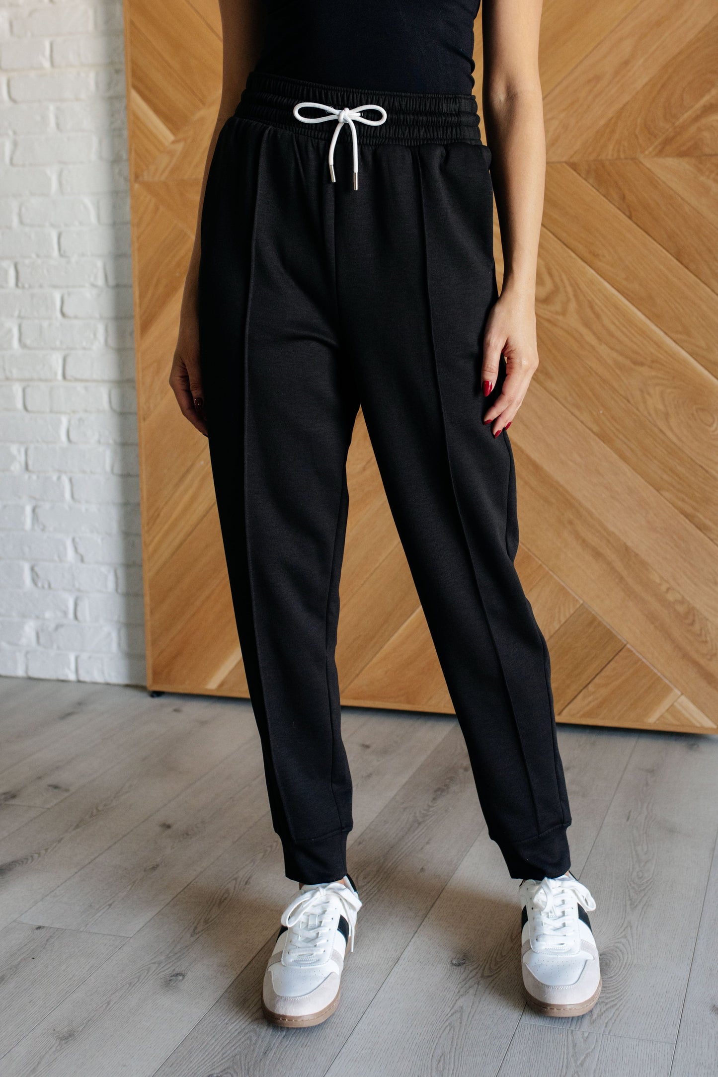 Center Seam Scuba Joggers in black featuring a front seam, elastic waistline with functional drawstring, side pockets, and banded hem for a comfortable and stylish fit.