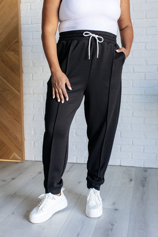 Center Seam Scuba Joggers in black featuring a front seam, elastic waistline with functional drawstring, side pockets, and banded hem for a comfortable and stylish fit.